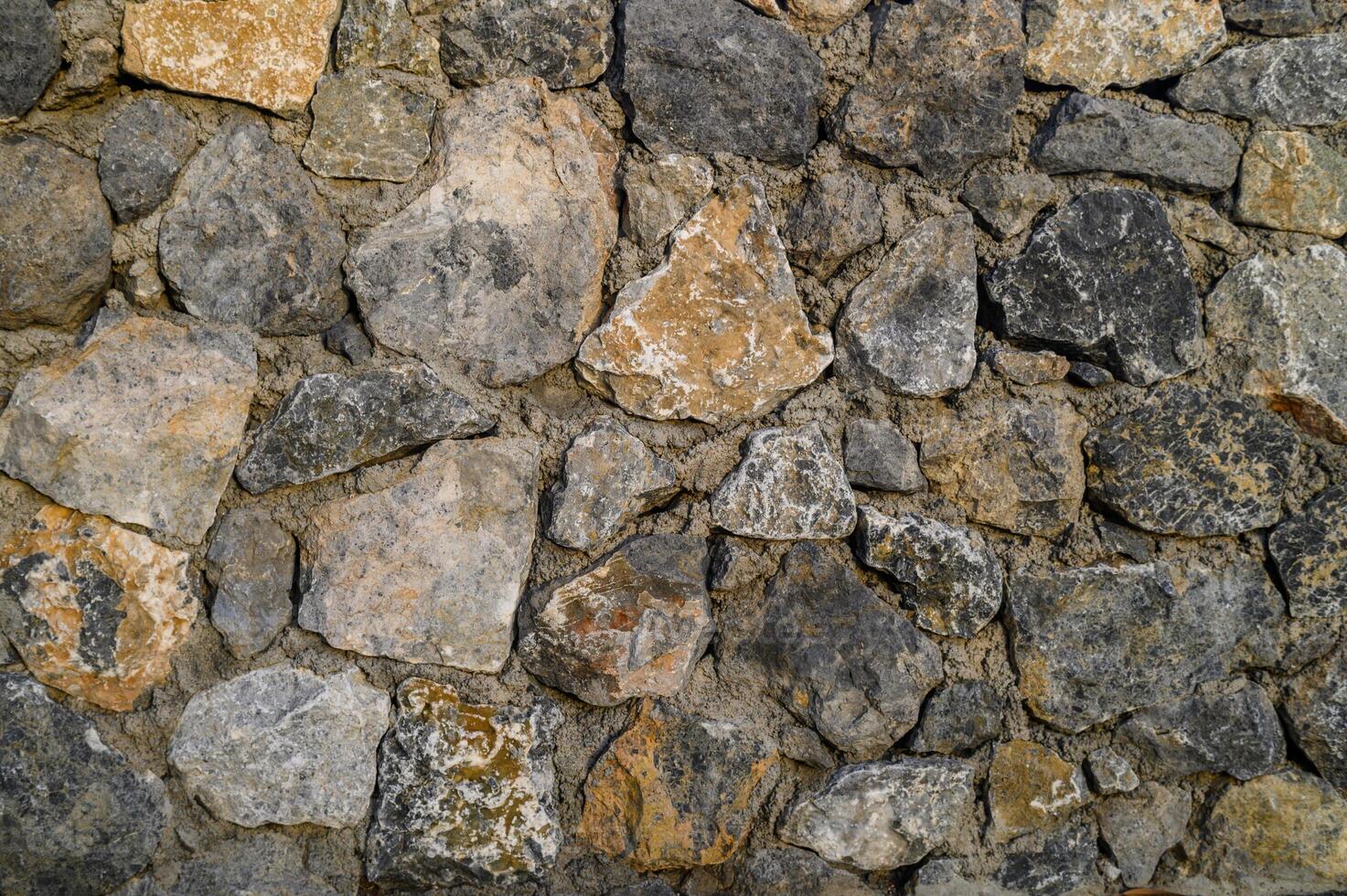 Unique patterns of natural stones create a rustic and textured wall in a tranquil outdoor setting photo