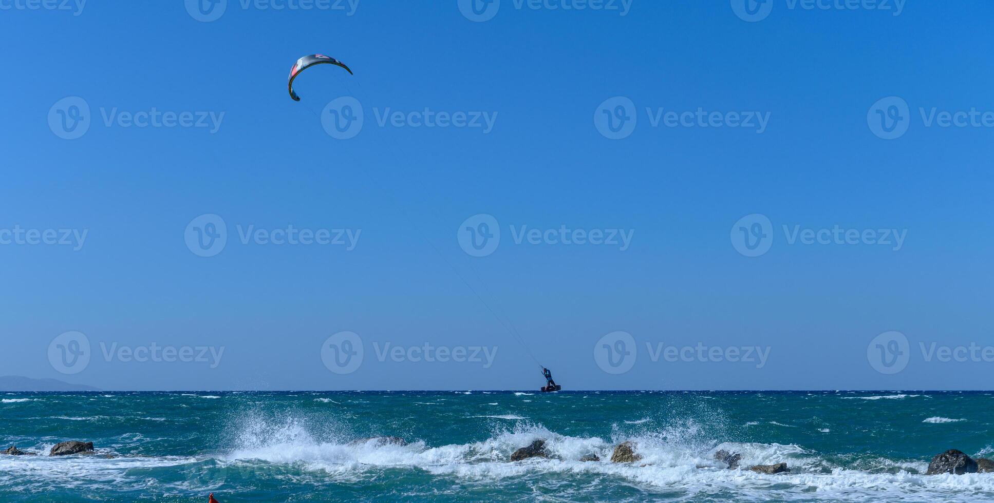 Kiteboarders dance across vibrant waters under a clear blue sky on a sunny coastal day photo