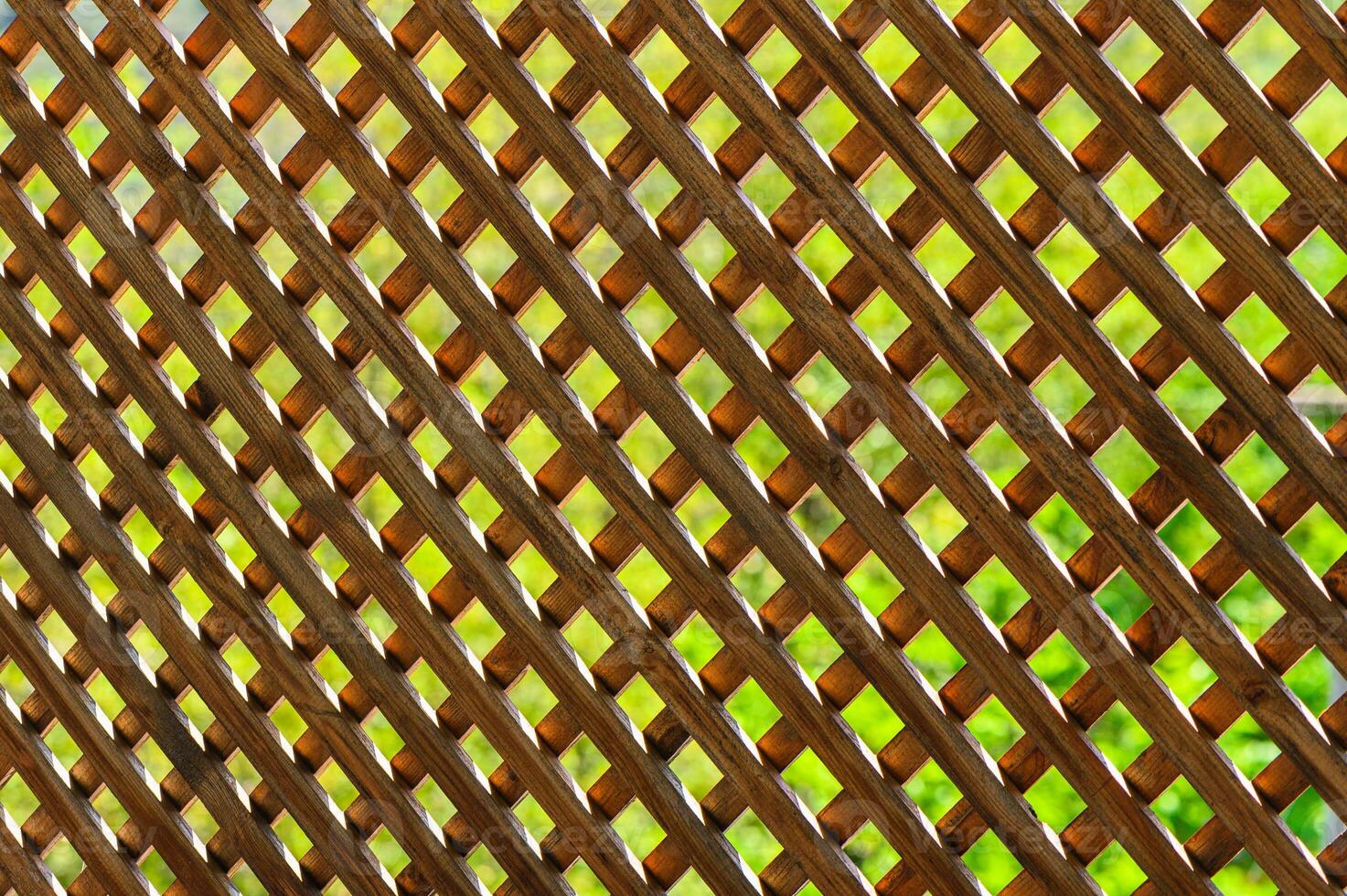 Intricate wooden lattice casting shadows in a lush garden setting during a bright afternoon photo