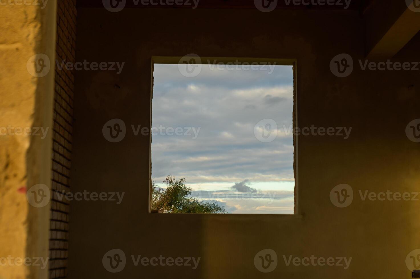 Open window reveals the beauty of the cloudy sky at dusk in a quiet, abandoned building photo