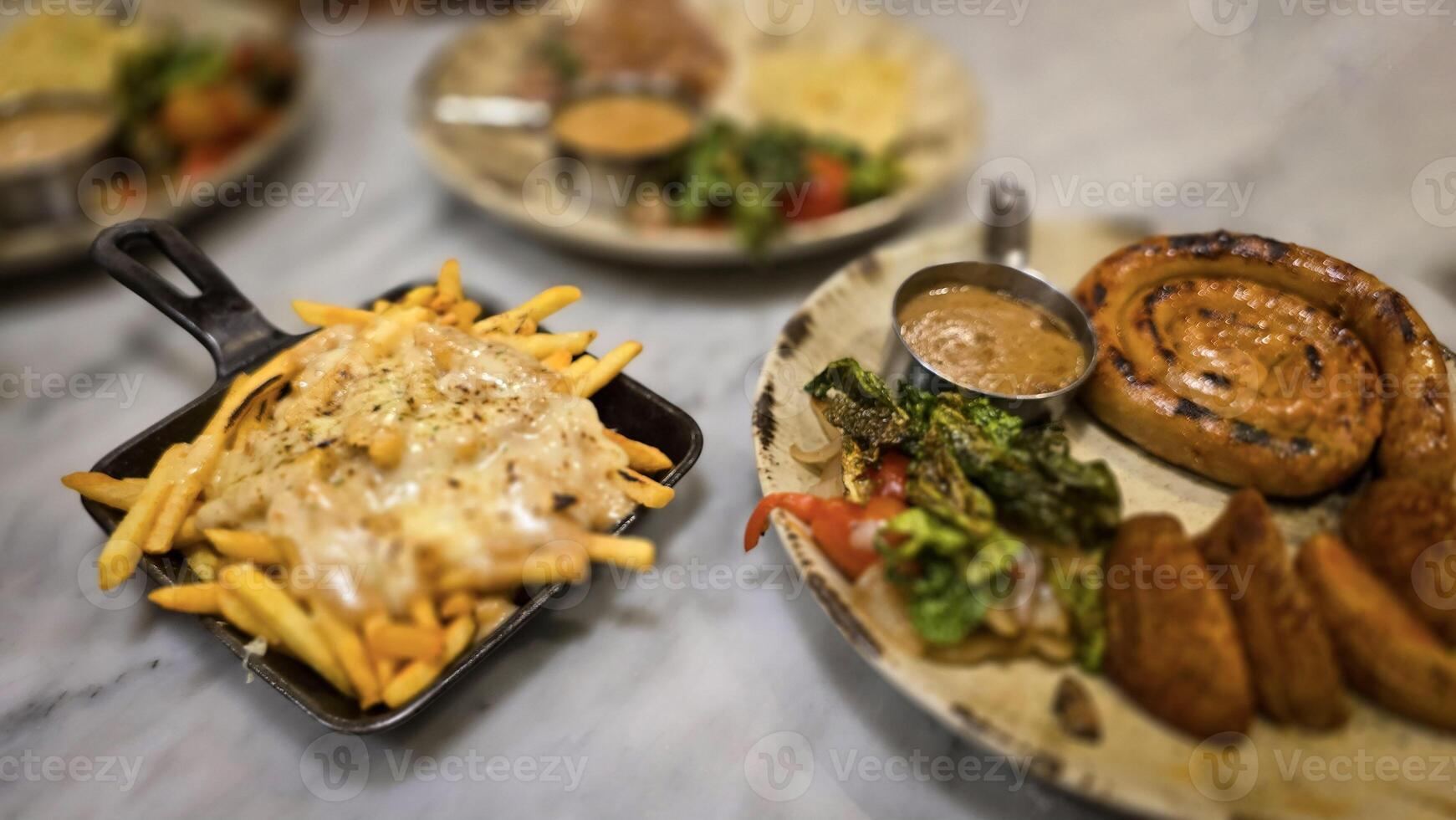 mouthwatering German worst curled up cumberland sausage meal featuring a grilled sausage, loaded cheese fries, and fresh vegetables served on a rustic plate photo