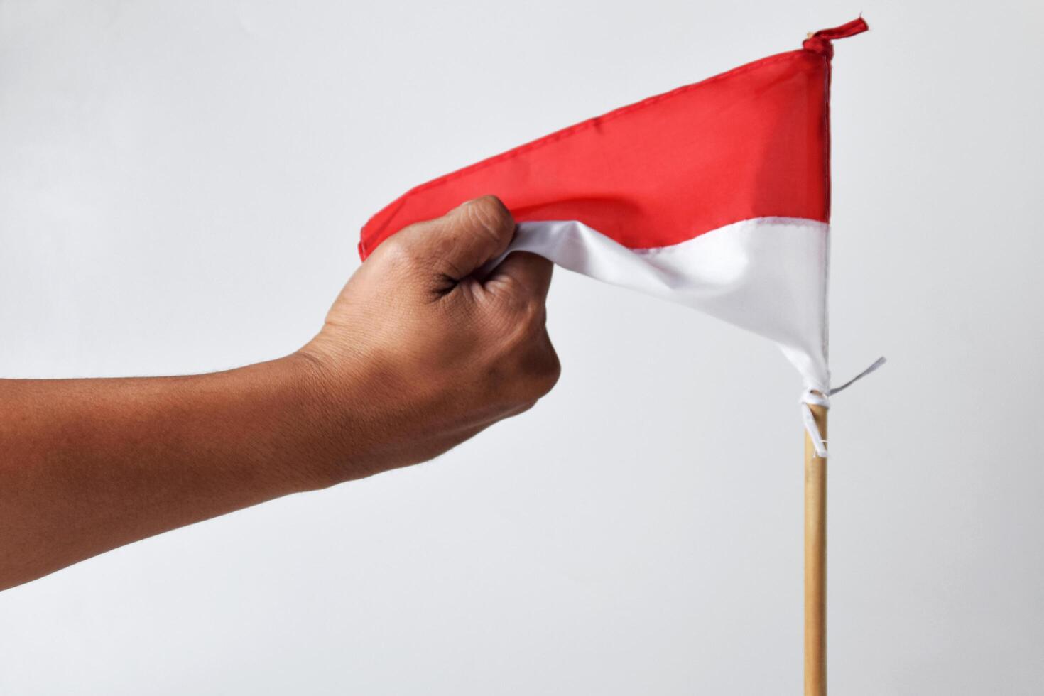 Someone is holding a red and white flag on a wooden pole photo