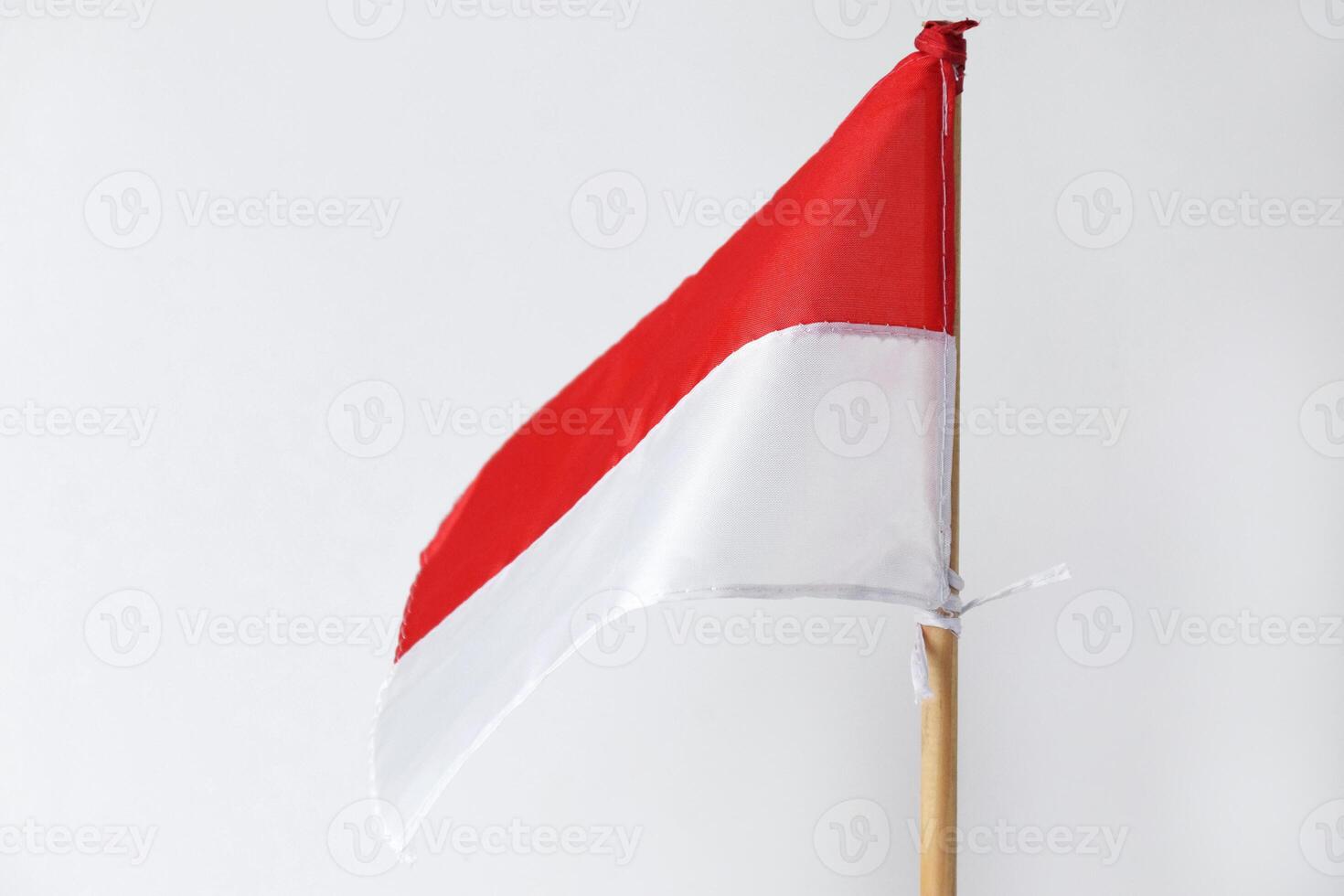 The red and white Indonesian flag with a wooden pole is on a white background photo