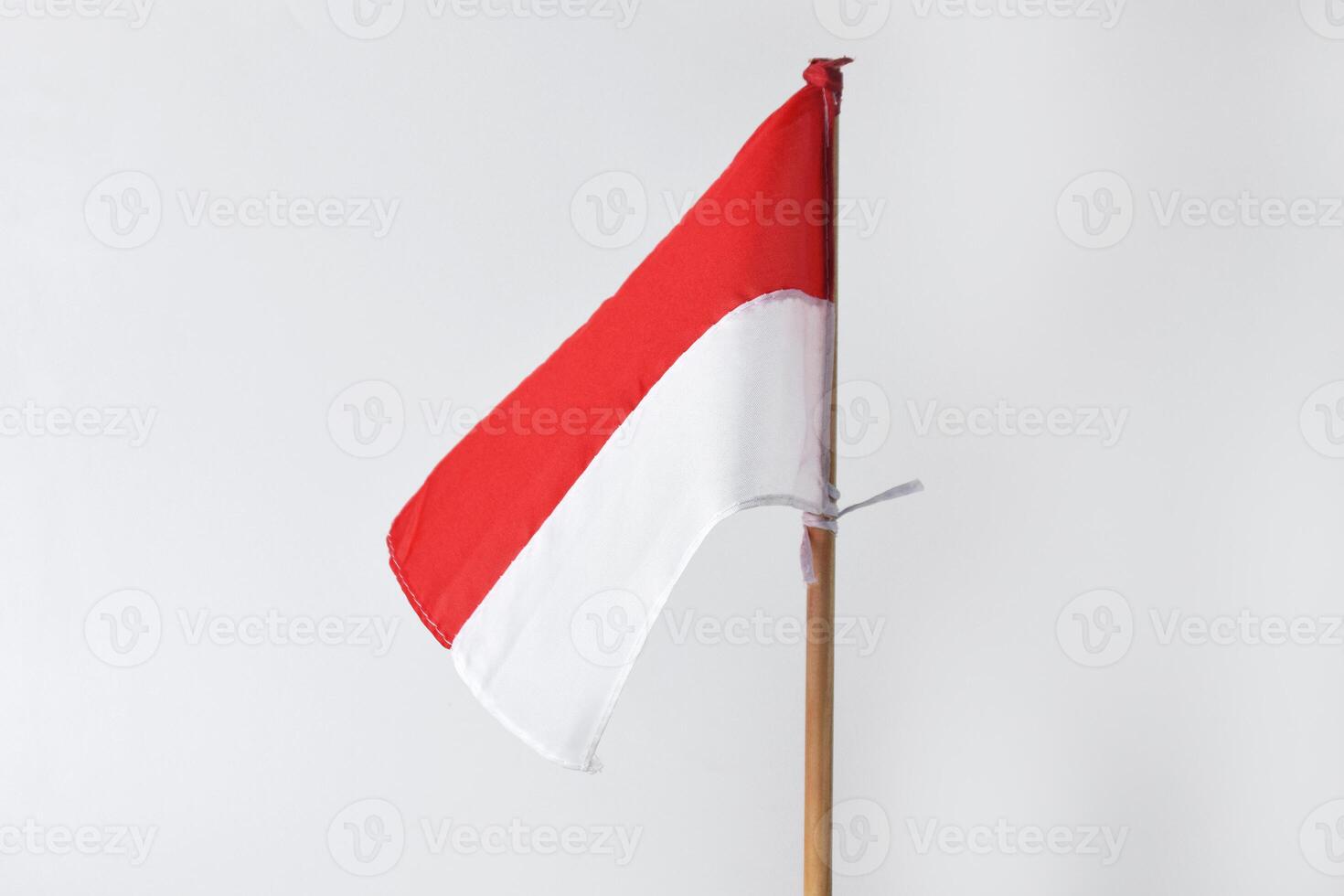 The red and white Indonesian flag with a wooden pole is on a white background photo