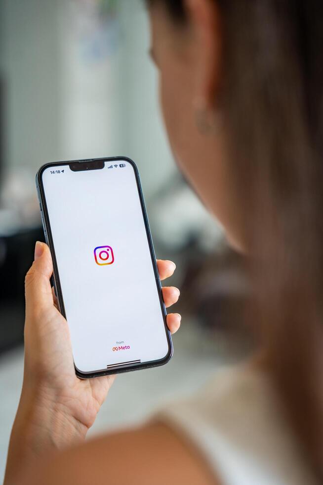 Prague, Czech republic - May 2, 2024. Woman holding iPhone with logo of application Instagram on the screen, using mobile application for business home. High quality photo
