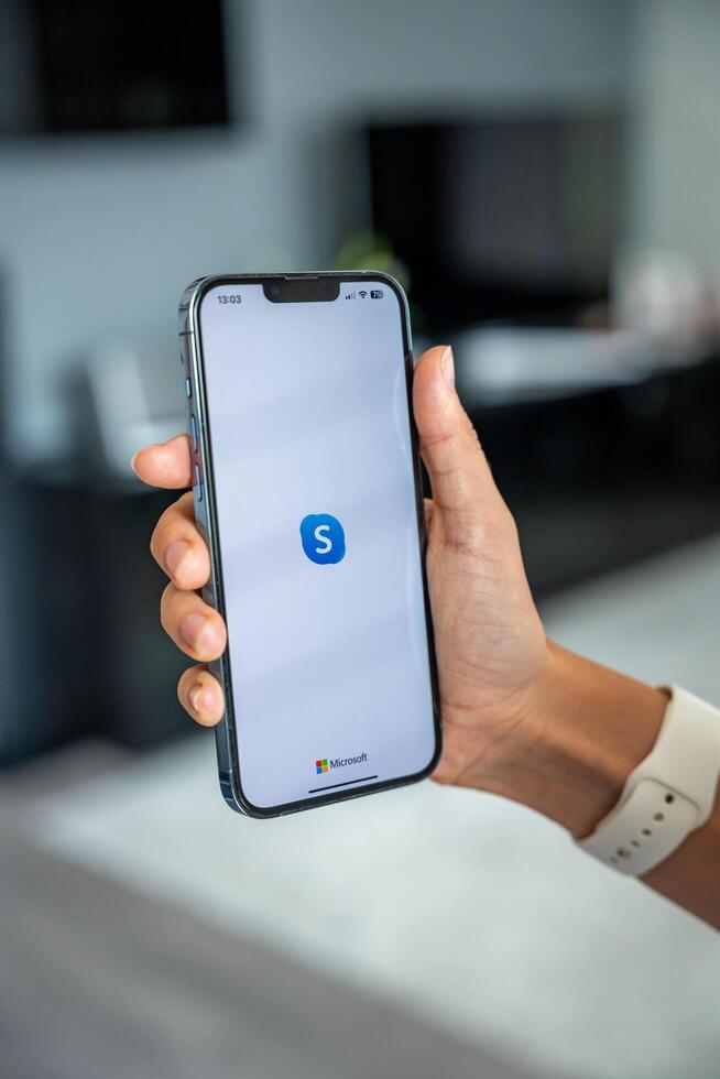 Prague, Czech republic - May 2, 2024. Woman holding iPhone with logo of application Skype on the screen, using mobile application for business home. High quality photo