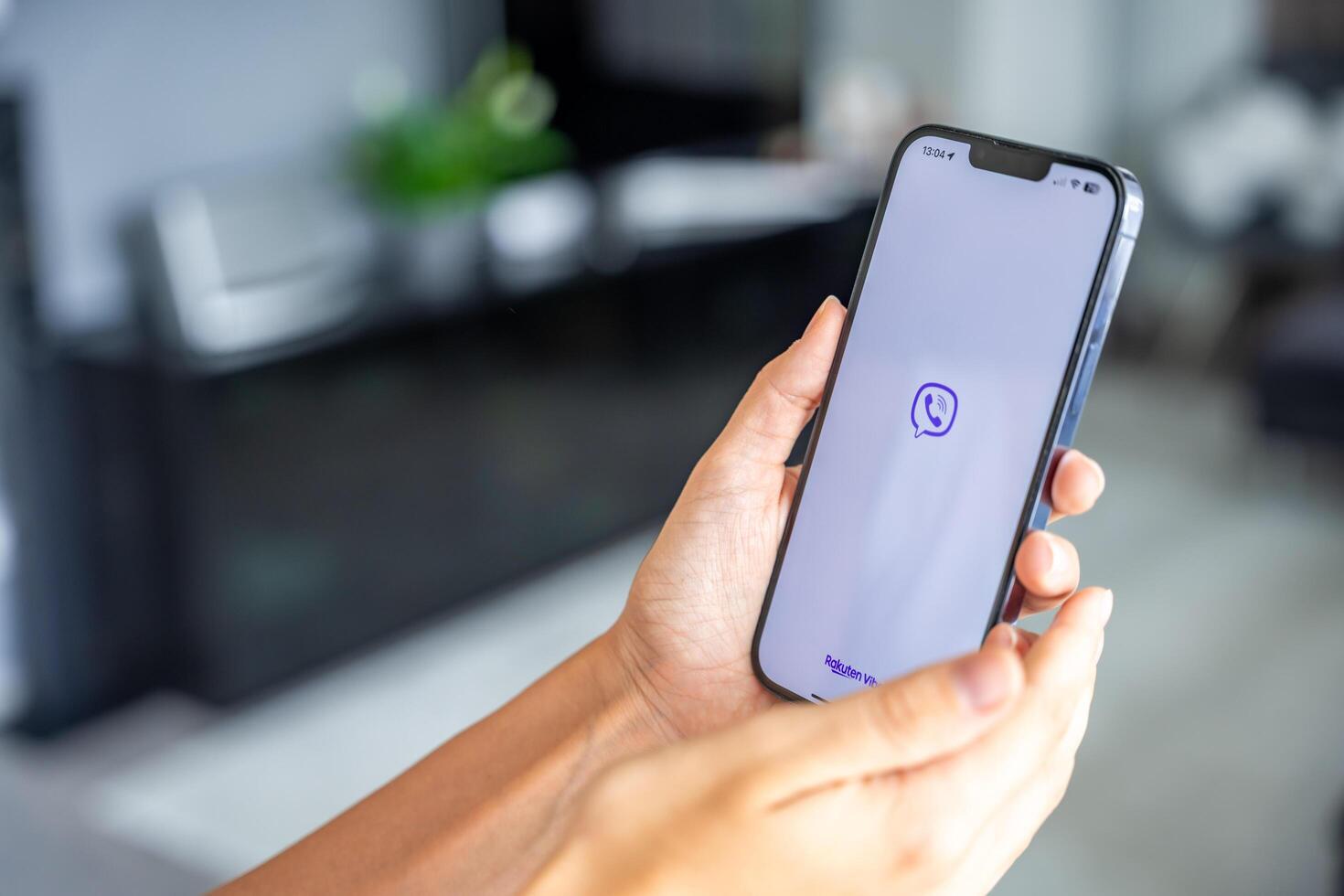 Prague, Czech republic - May 2, 2024. Woman holding iPhone with logo of application Rakuten Viber on the screen, using mobile application for business home. High quality photo