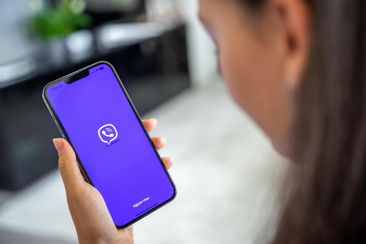 Prague, Czech republic - May 2, 2024. Woman holding iPhone with logo of application Rakuten Viber on the screen, using mobile application for business home. High quality photo