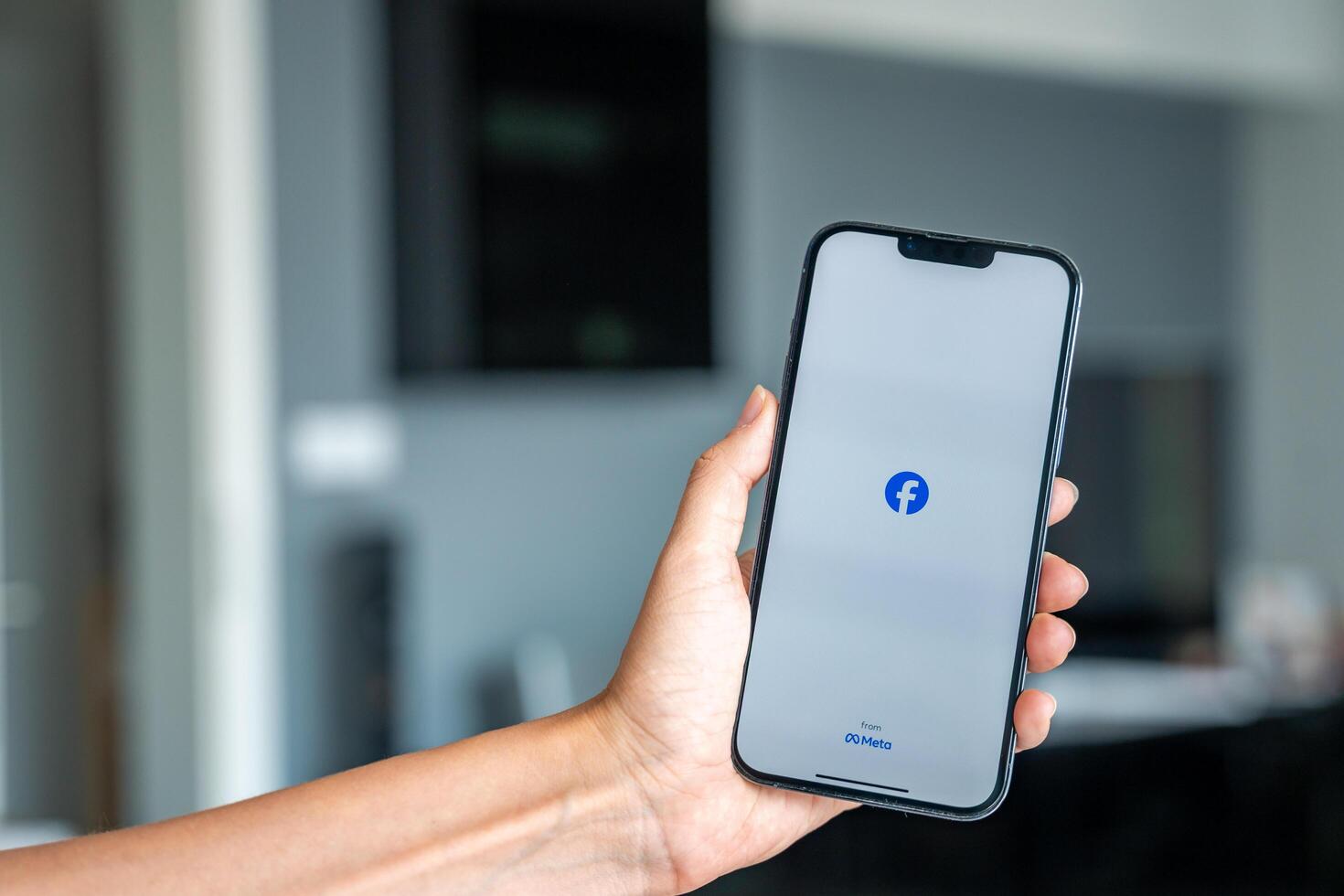 Prague, Czech republic - May 2, 2024. Woman holding iPhone with logo of application Meta Facebook on the screen, using mobile application for business home. High quality photo