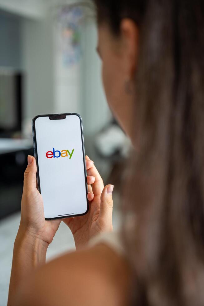 Prague, Czech republic - May 2, 2024. Woman holding iPhone with logo of application Ebay on the screen, using mobile application . High quality photo