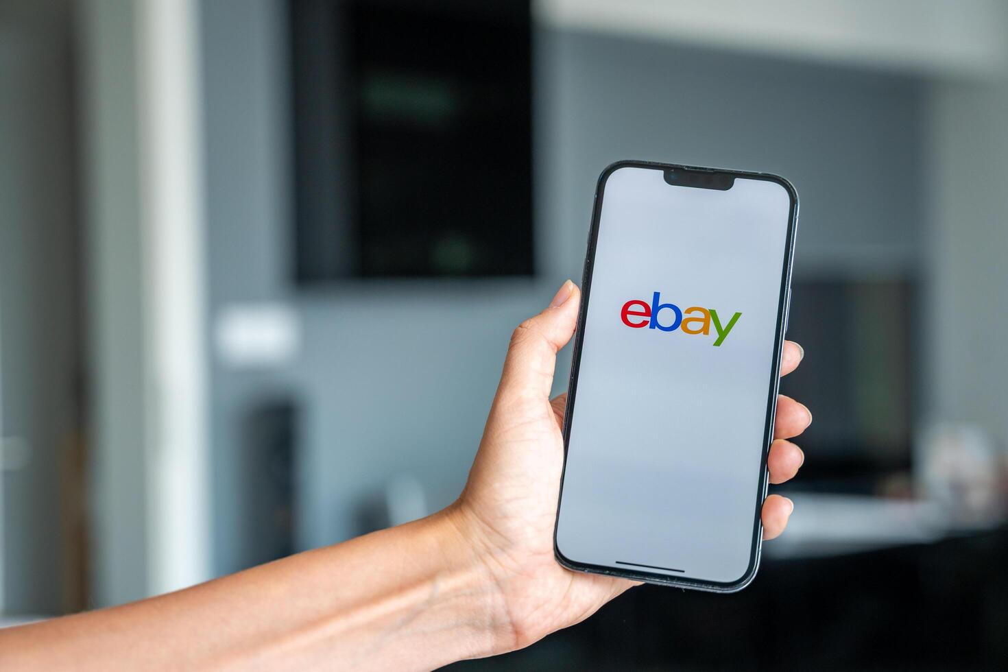 Prague, Czech republic - May 2, 2024. Woman holding iPhone with logo of application Ebay on the screen, using mobile application . High quality photo