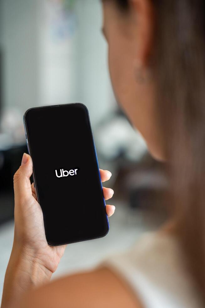 Prague, Czech republic - May 2, 2024. Woman holding iPhone with logo of application Uber on the screen, using mobile application . High quality photo