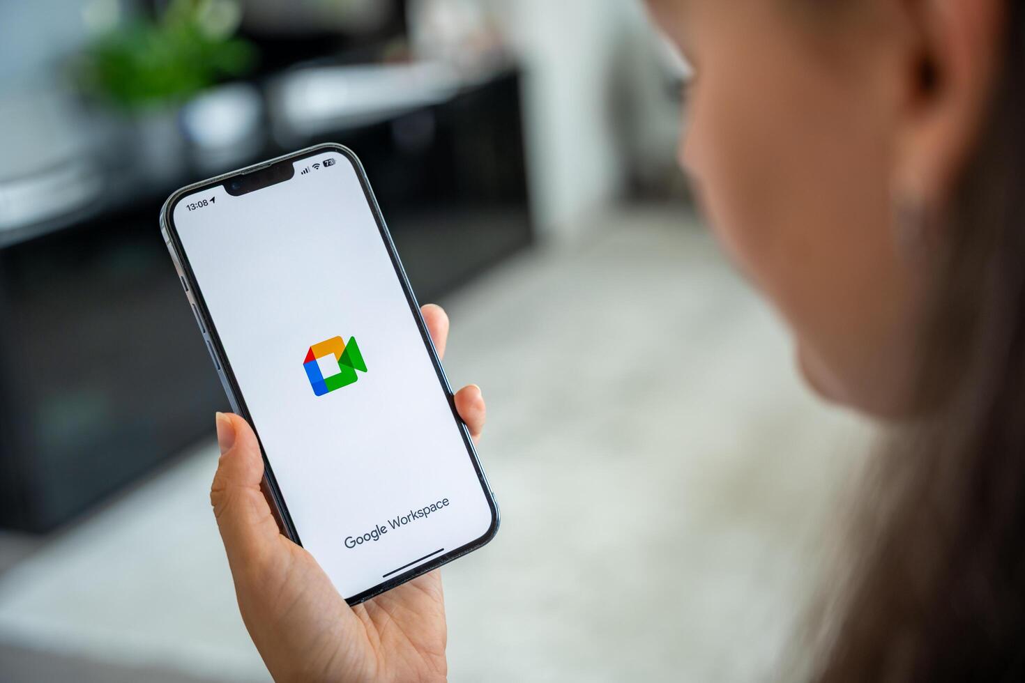 Prague, Czech republic - May 2, 2024. Woman holding iPhone with logo of application Goole Meet on the screen, using mobile application for business home. High quality photo