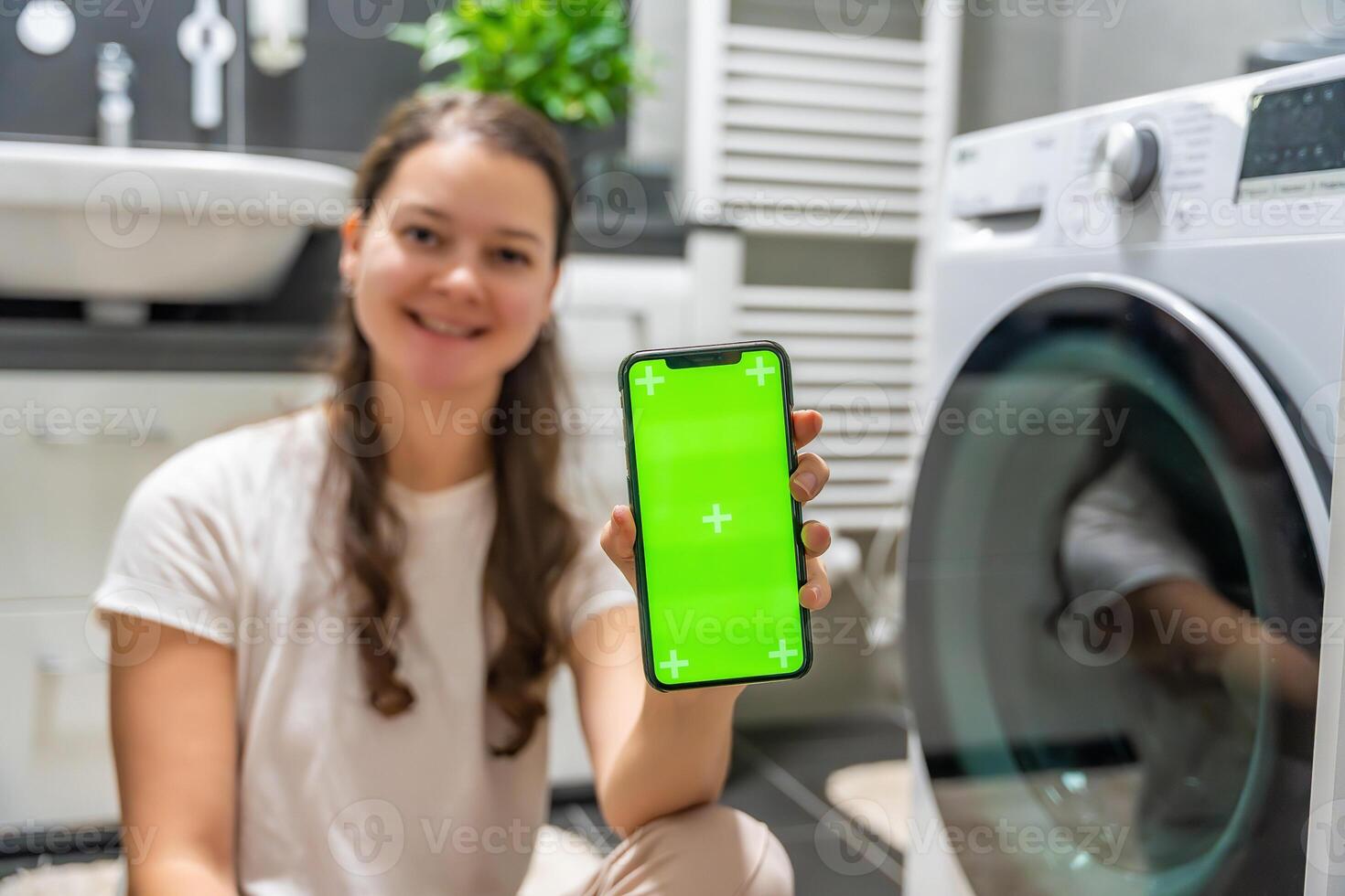 Young woman using mobile phone control via wi-fi and app for washing machine in home. Homesmart app, chroma key green screen. High quality photo