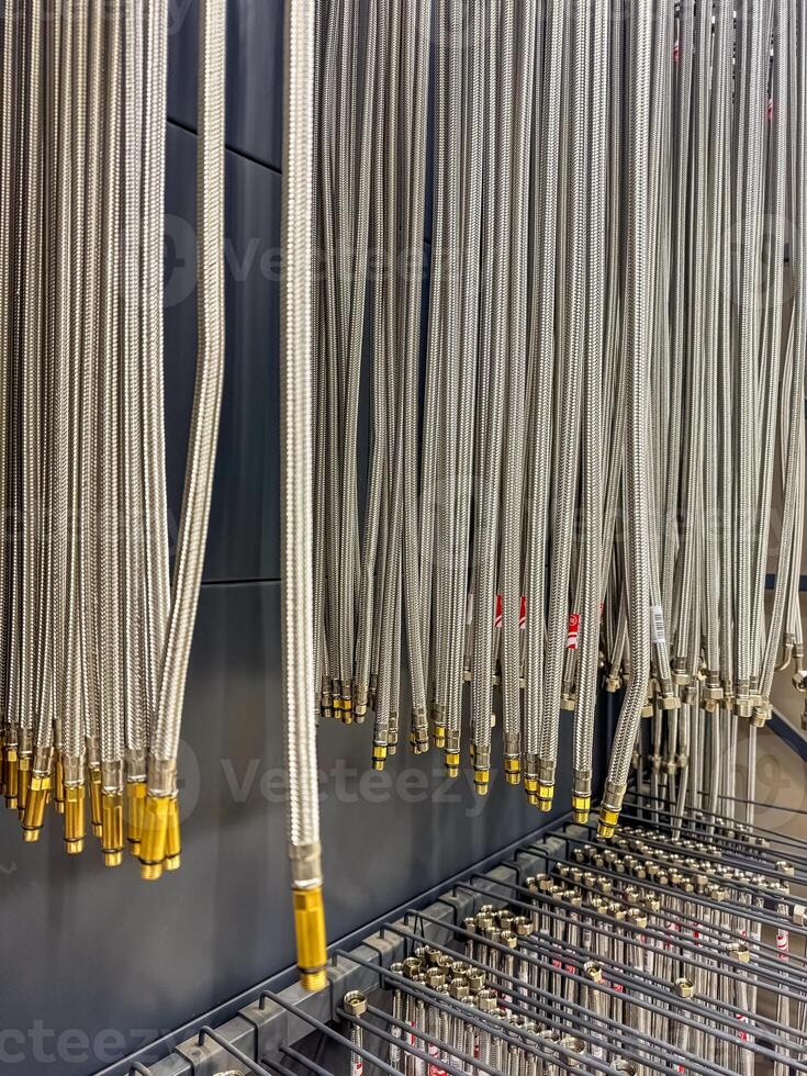 Hanging braided metal hoses with golden connectors in a hardware store. High quality photo