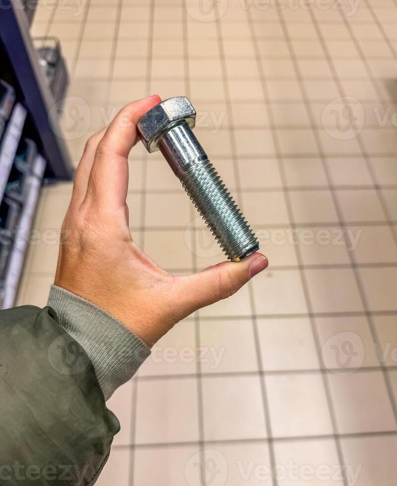 female hand holding large bolt in warehouse . High quality photo