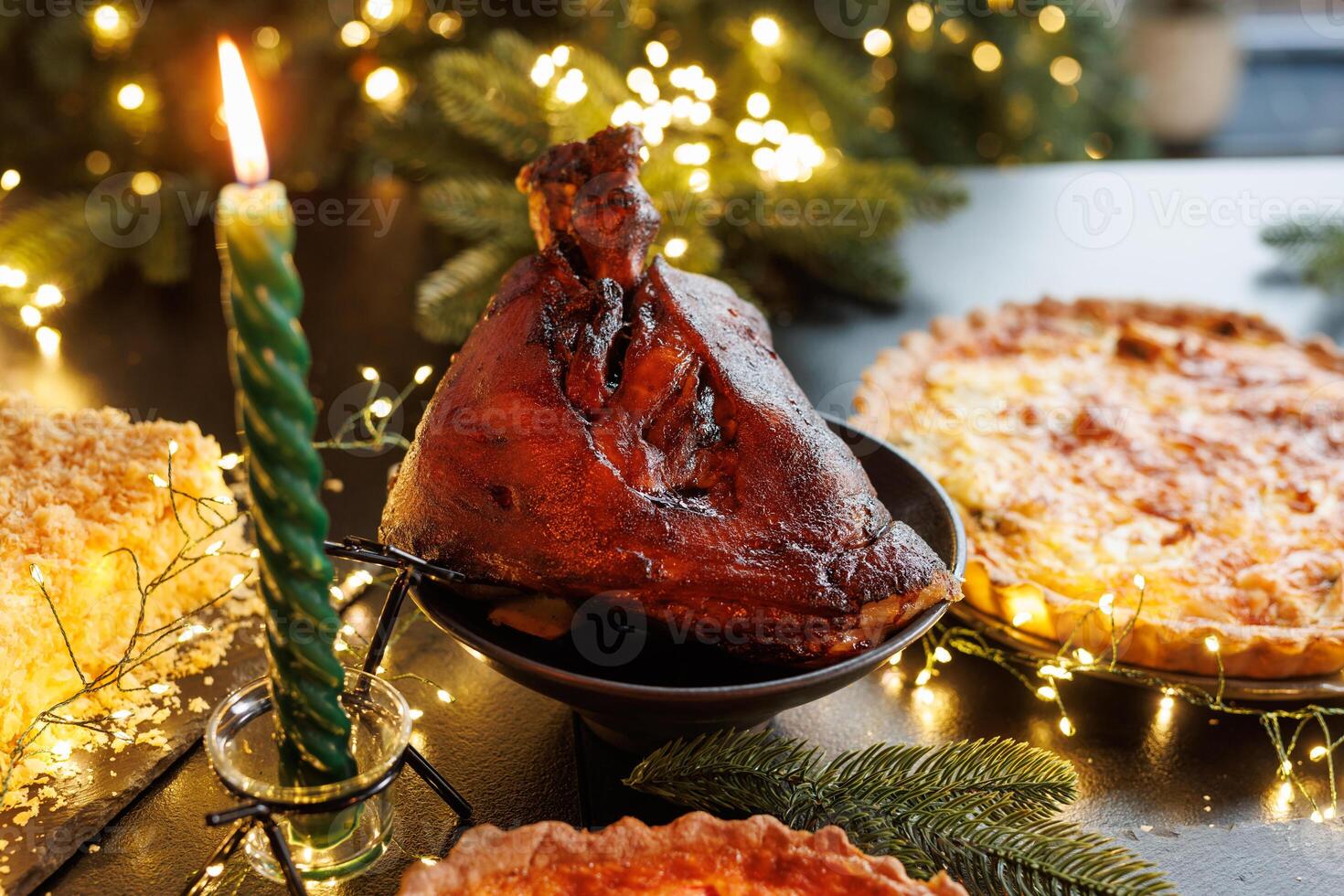 Festive table with roasted knuckle, cozy Christmas evening with festive dishes, candles and garlands photo