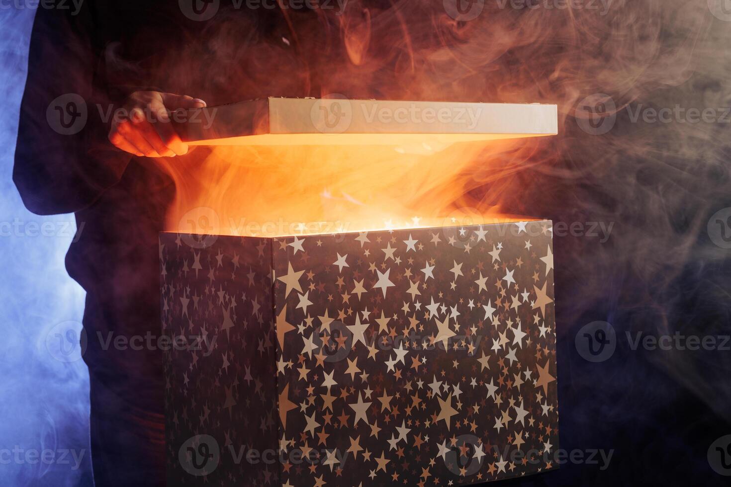human hands taking out surprise from mysterious box on dark red background surrounded by smoke photo