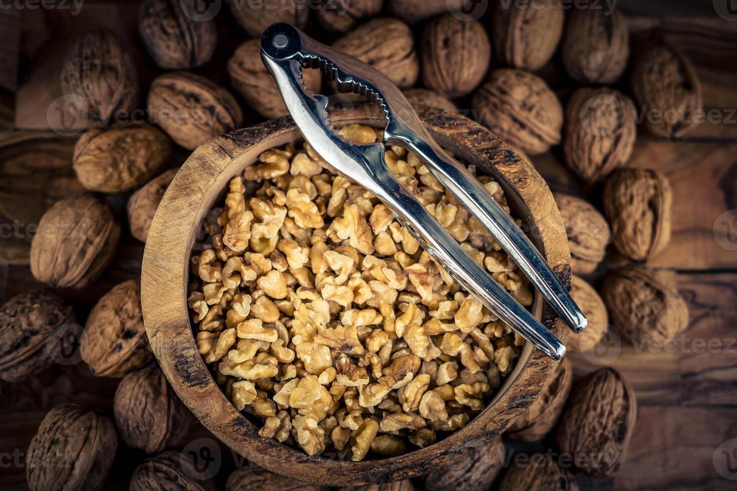Fresh and cracked walnuts on olive wood photo