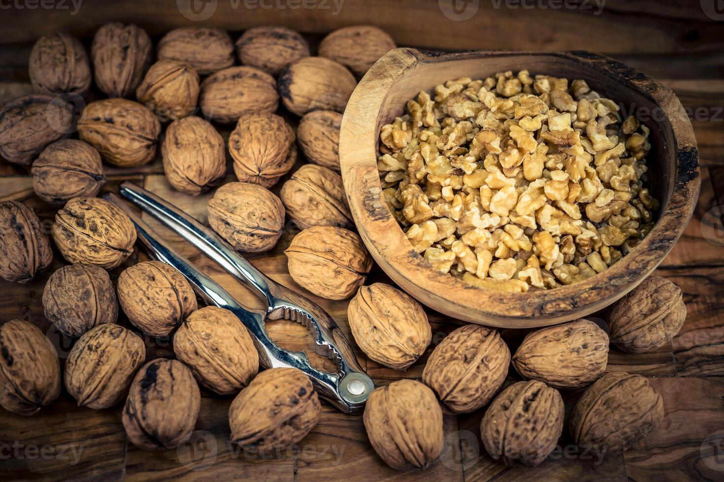 Fresh and cracked walnuts on olive wood photo