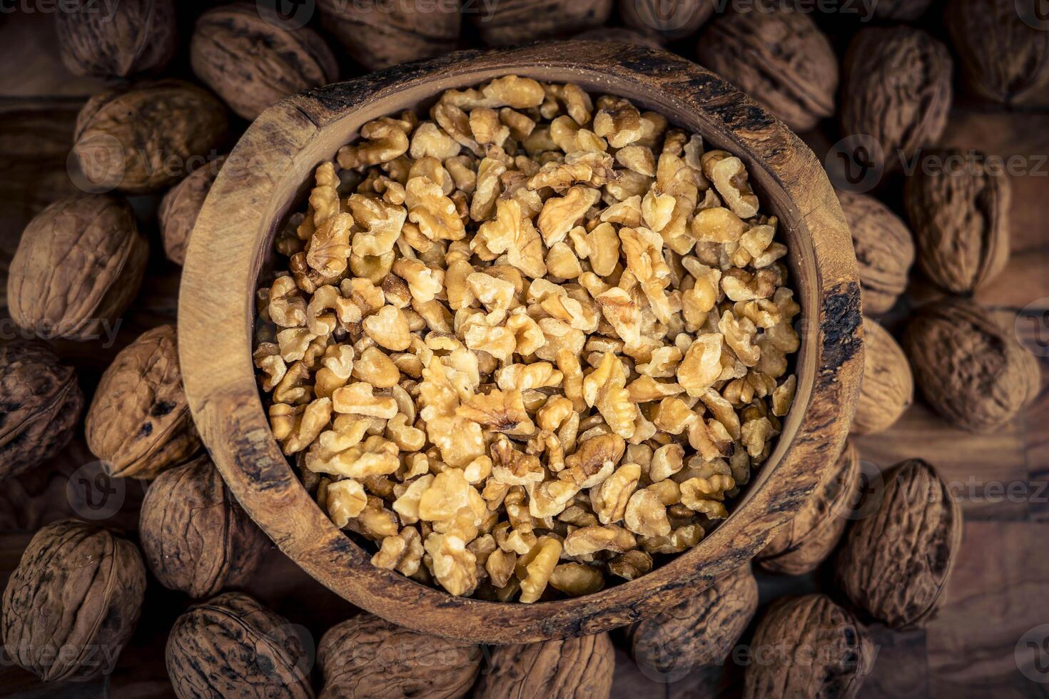 Fresh and cracked walnuts on olive wood photo