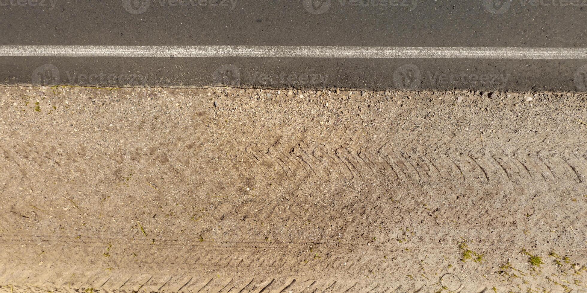 view from above on texture of asphalt road with median from gravel road with lawn photo