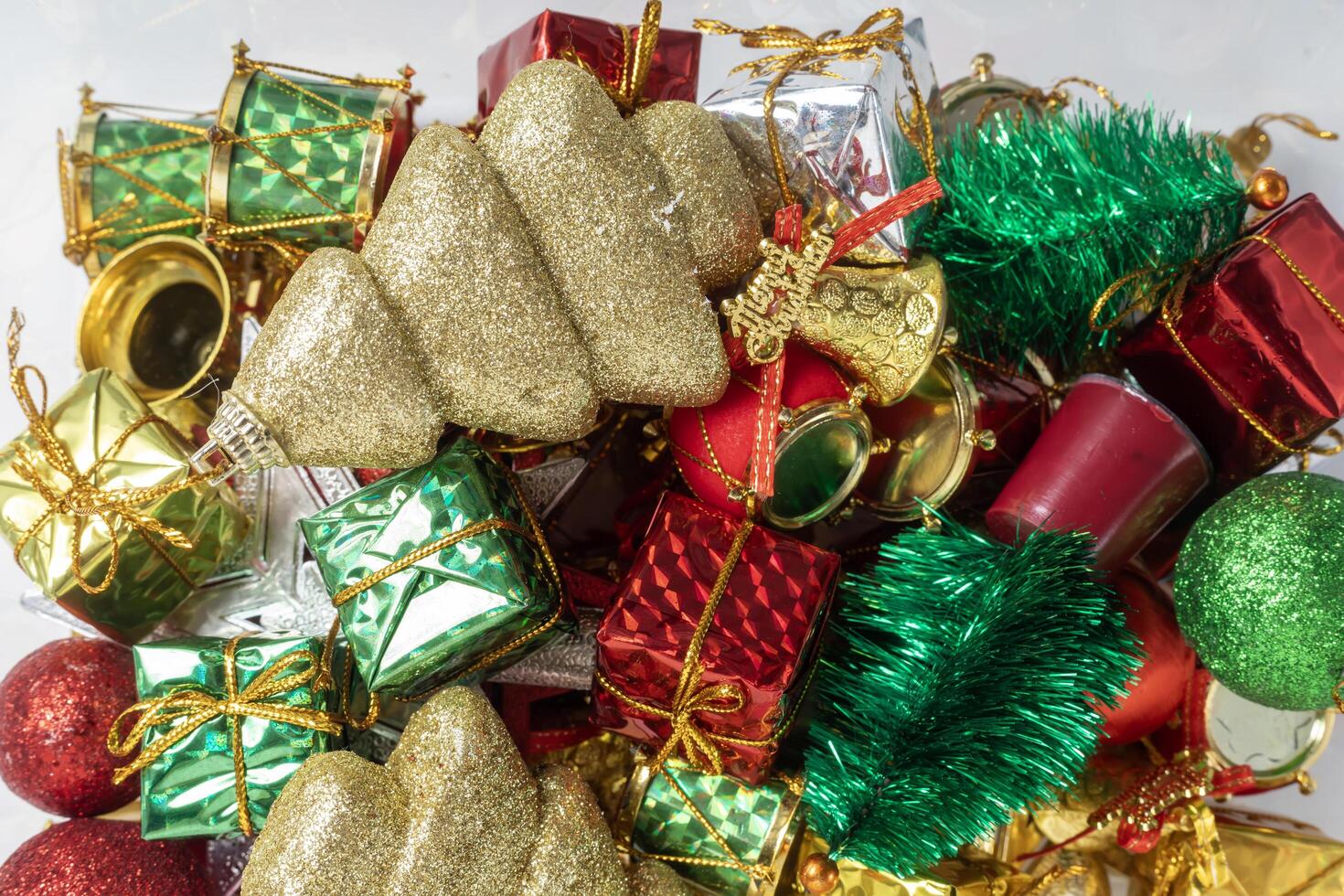 Pile of colorful Christmas decorations with shiny ornaments and gifts, top view photo