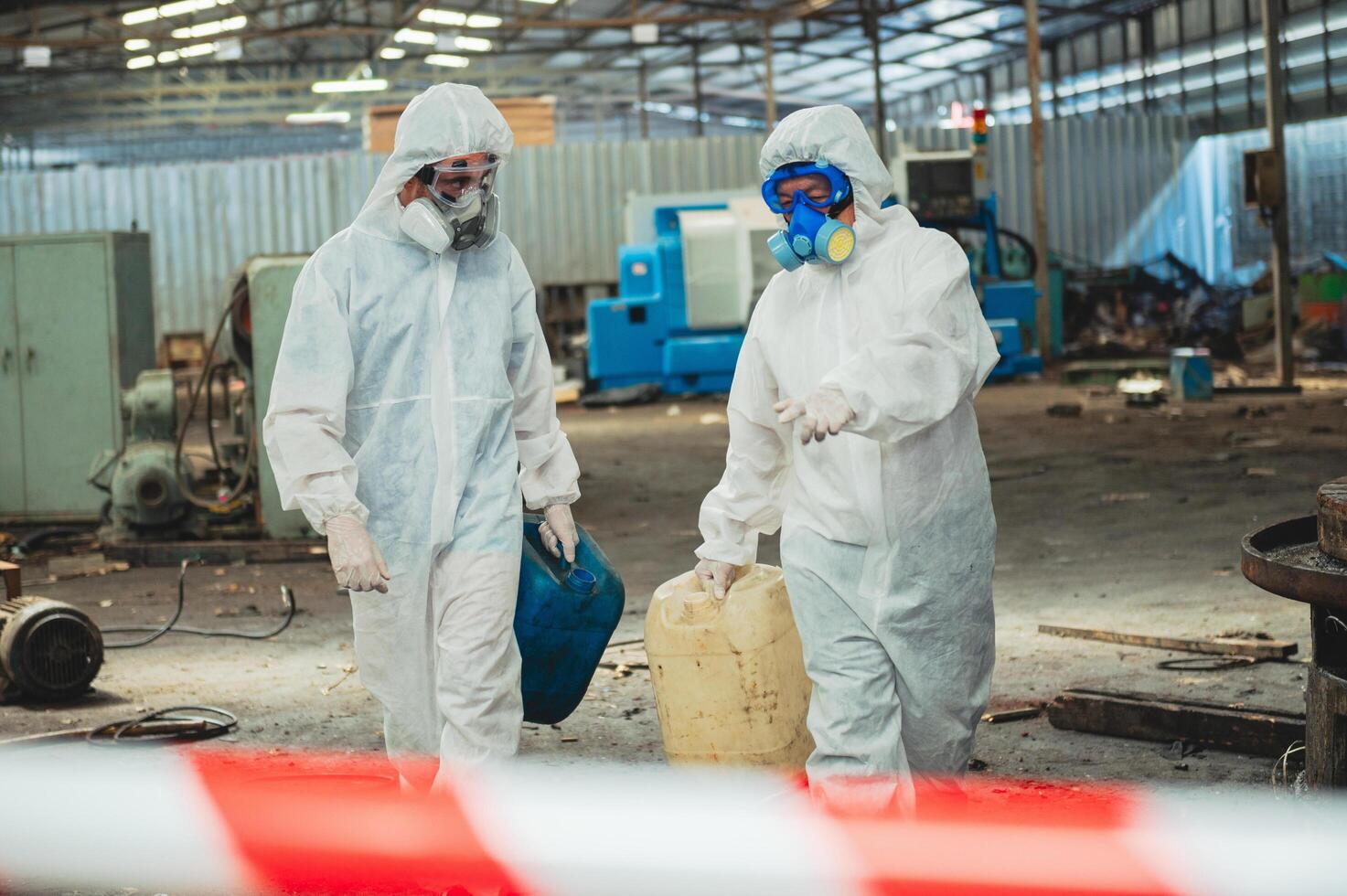 Two people in hazmat suits are walking through a dirty industrial area photo