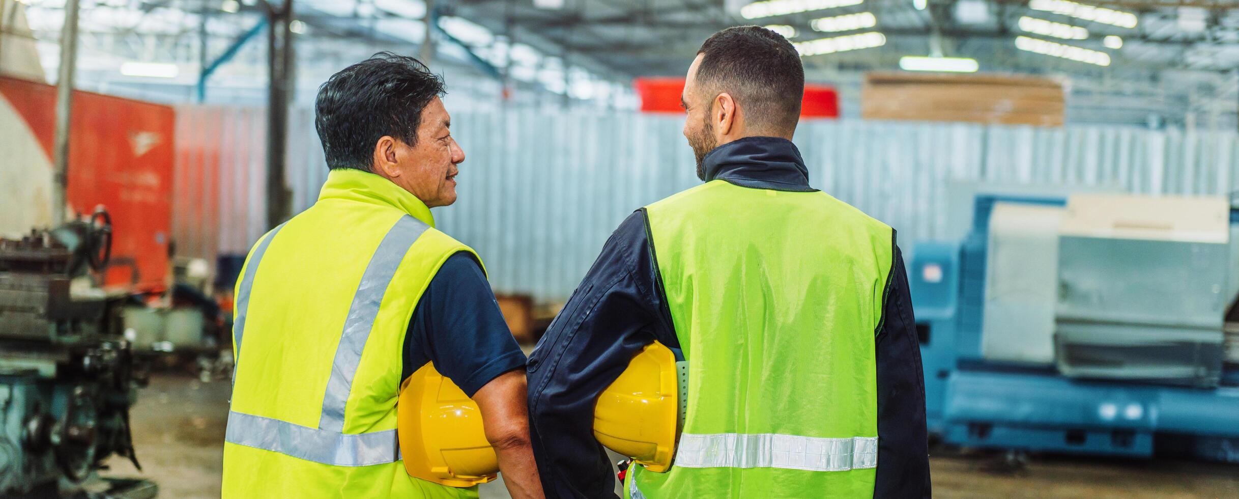 Two men in safety gear are standing in a factory photo