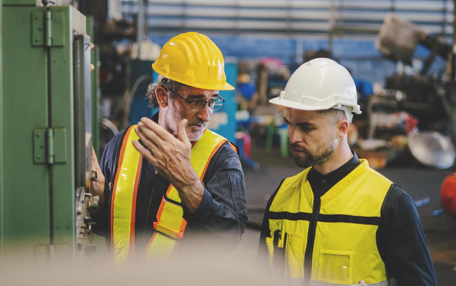 Two men in safety gear are looking at a machine photo