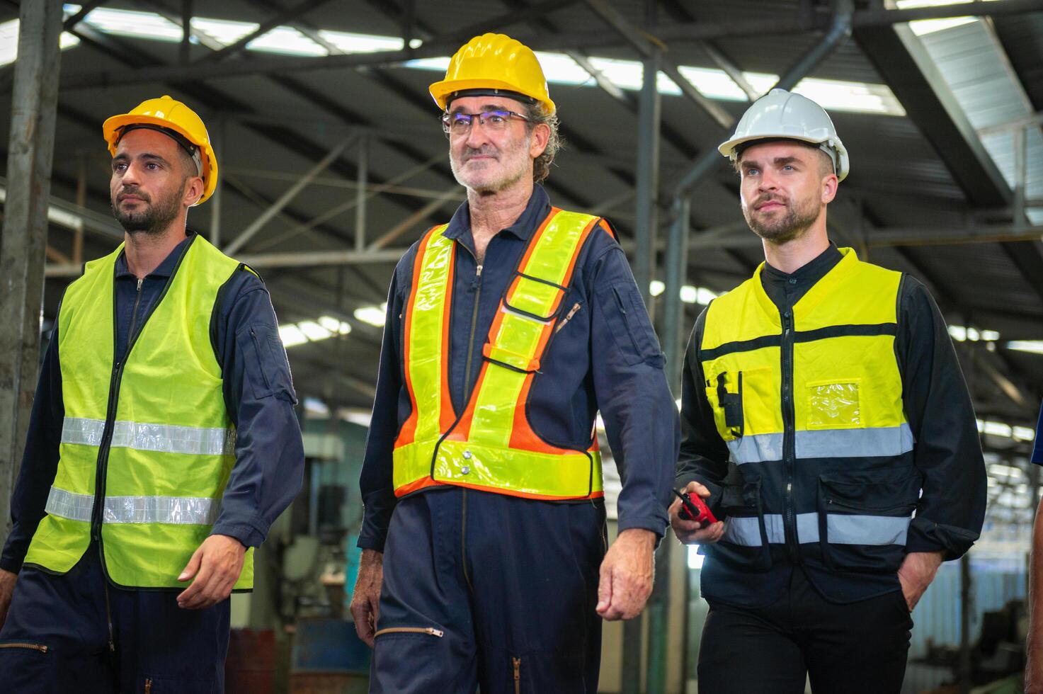 Three men in safety gear walk together in a factory photo