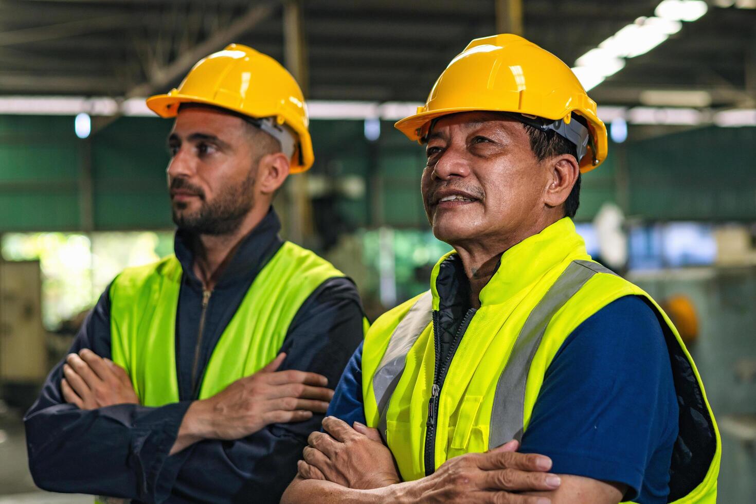 Two men wearing safety gear and yellow helmets stand next to each other photo