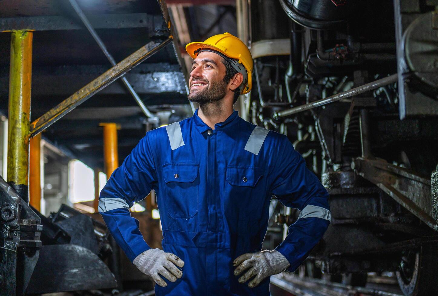 man in a blue and yellow safety suit stands in front of a train engine photo