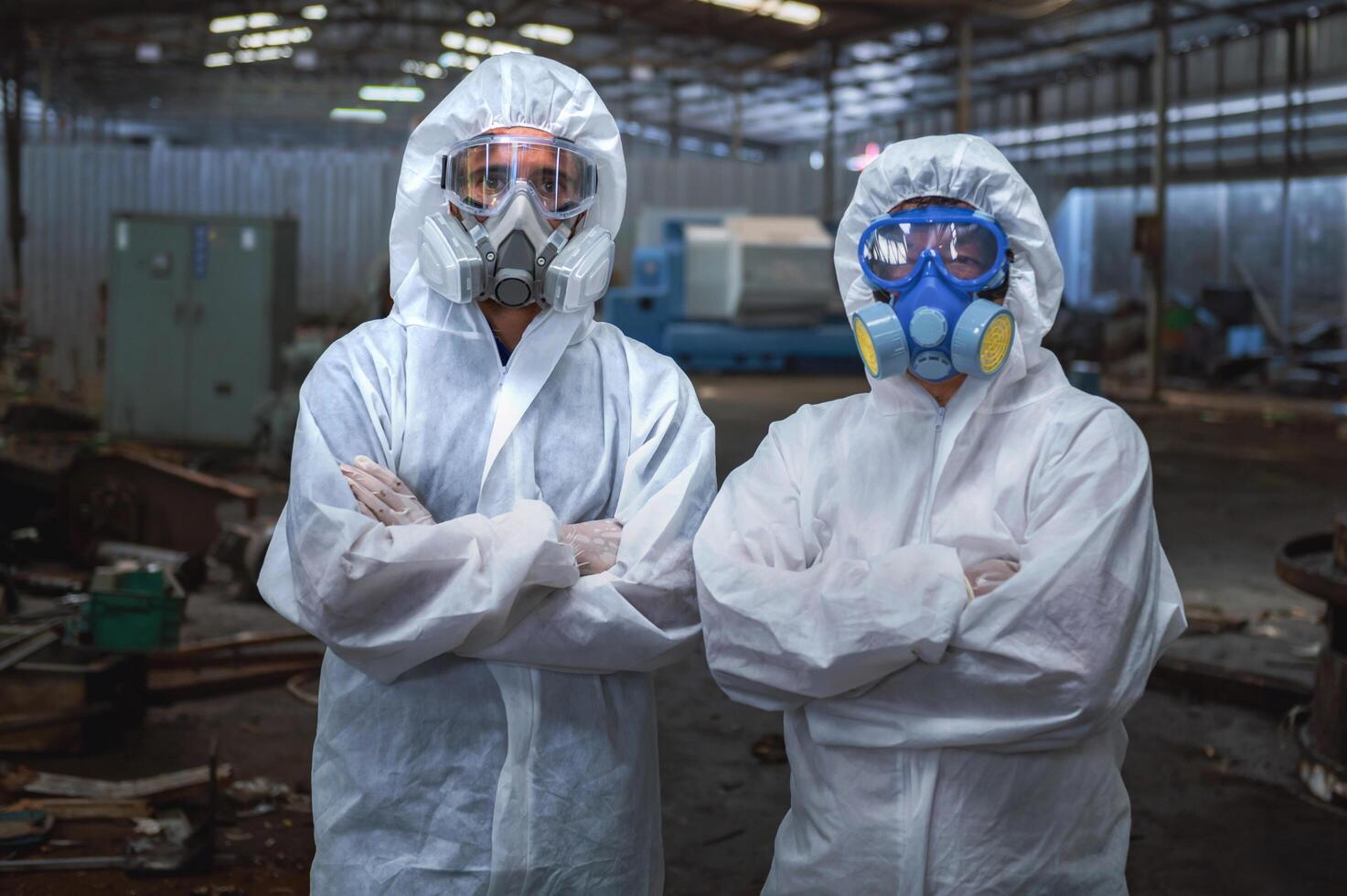 Two people in white protective gear are standing in front of a building photo