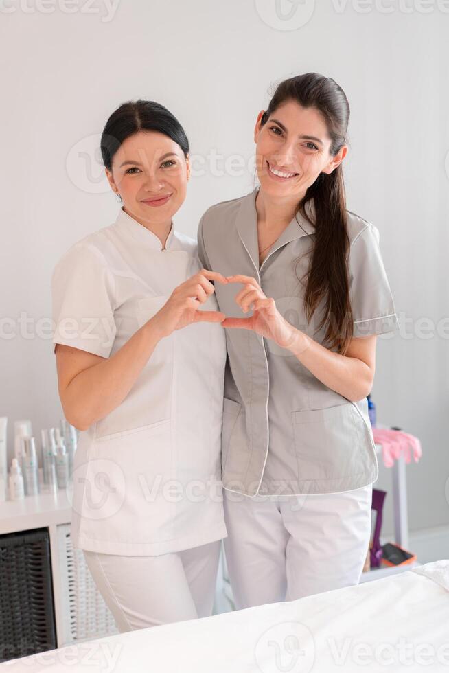 Happy female doctors making heart shape with hands at clinic photo