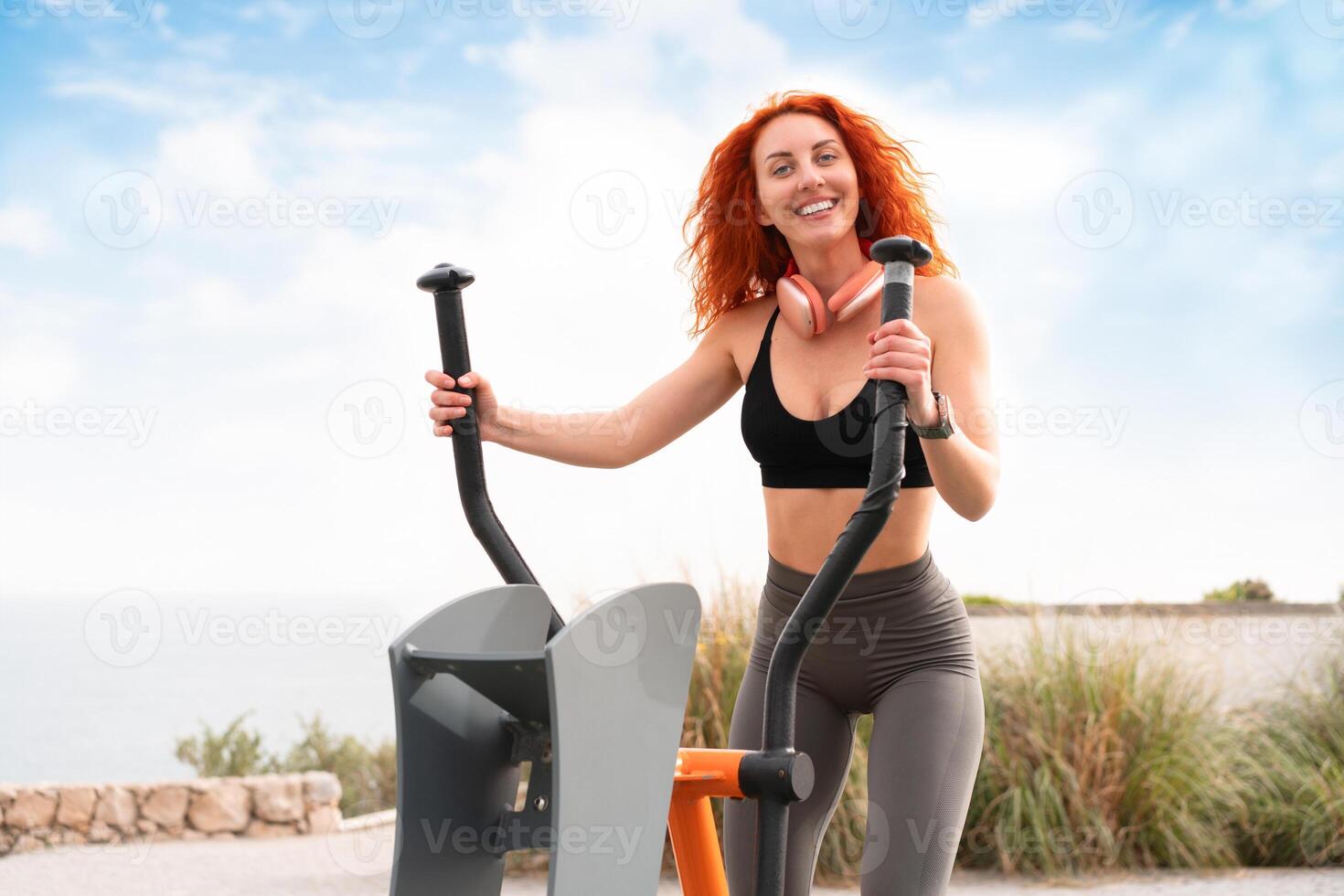 Cheerful sporty woman exercising on stepper machine at outdoor gym photo