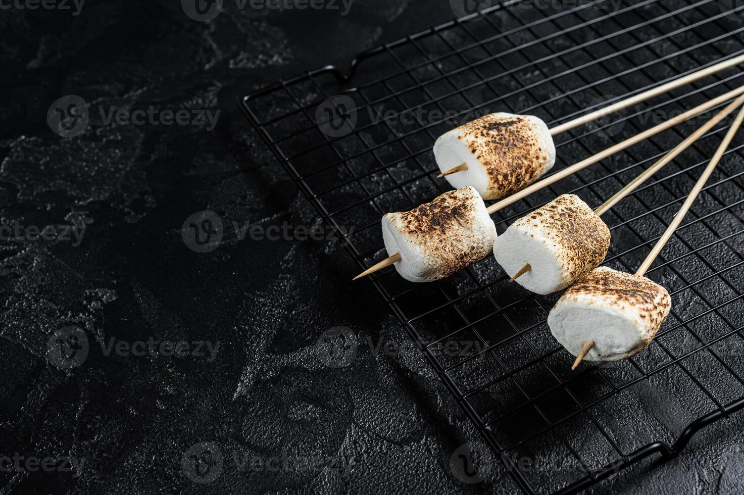 BBQ Grilled Marshmallow on the sticks. Black background. Top view. Copy space photo