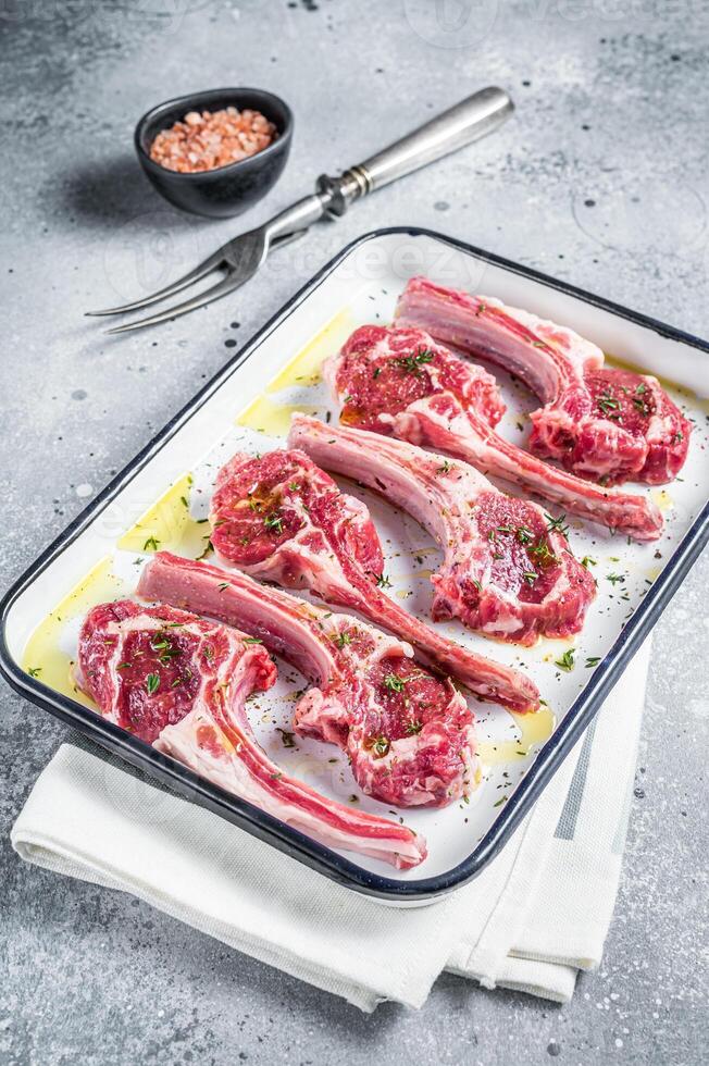 Ready for cooking raw lamb chop steaks with spices and herbs. Gray background. Top view photo