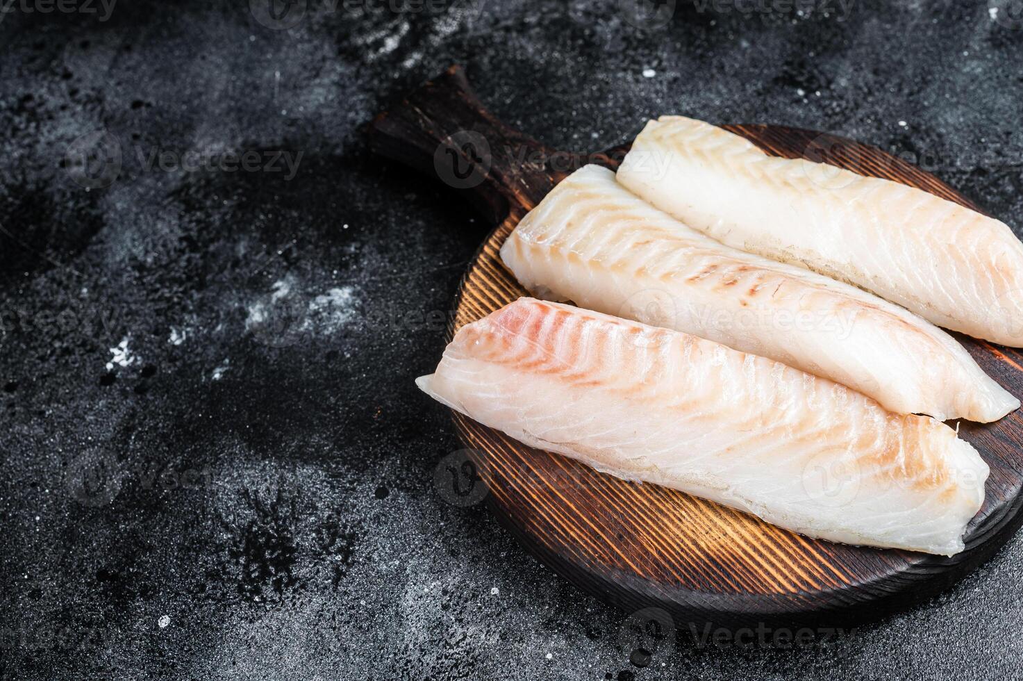 Fillets of codfish, raw cod fish meat. Black background. Top view. Copy space photo