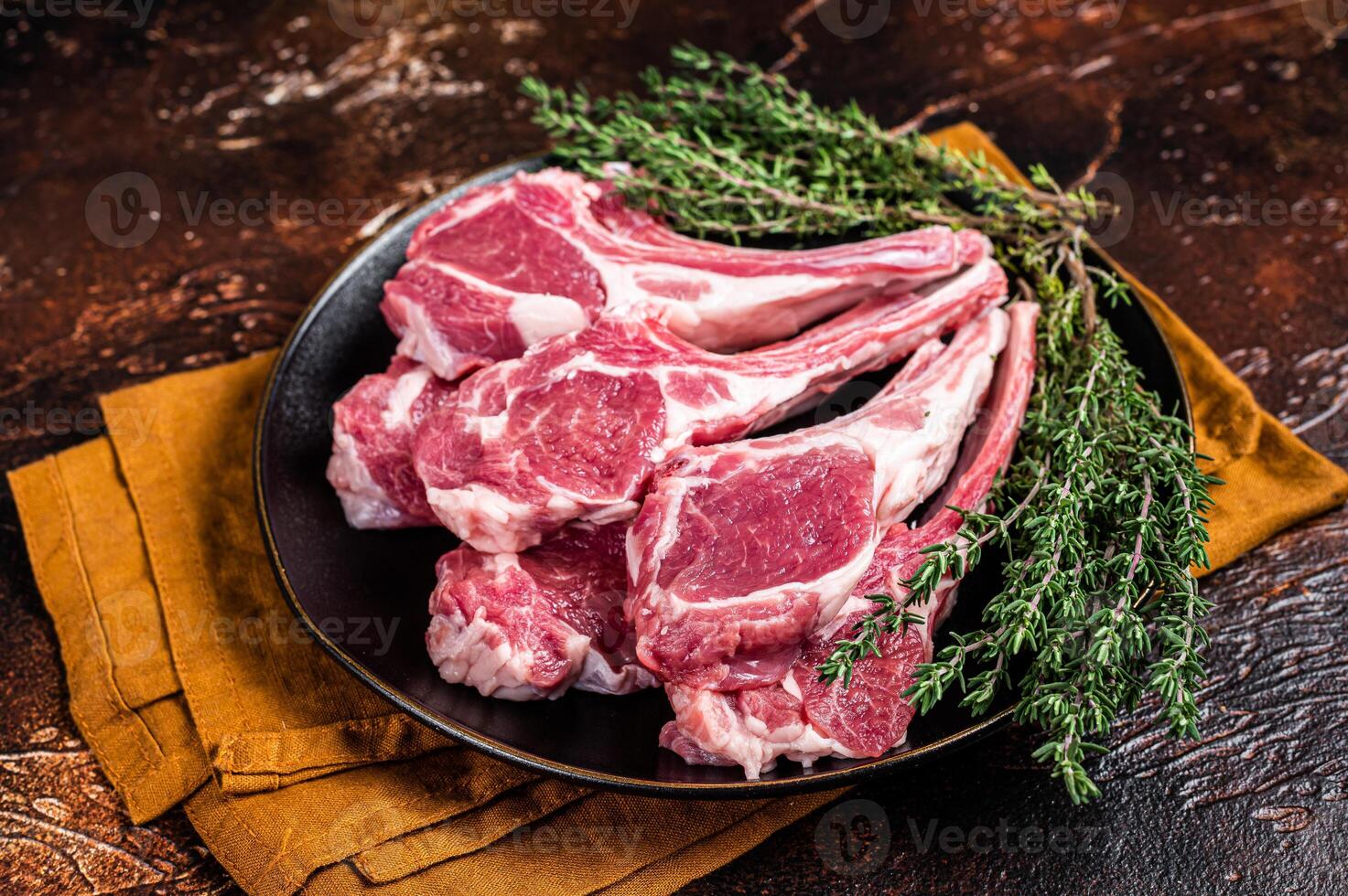 Raw lamb chops, fresh mutton meat cutlets on a ribs. Dark background. Top view photo