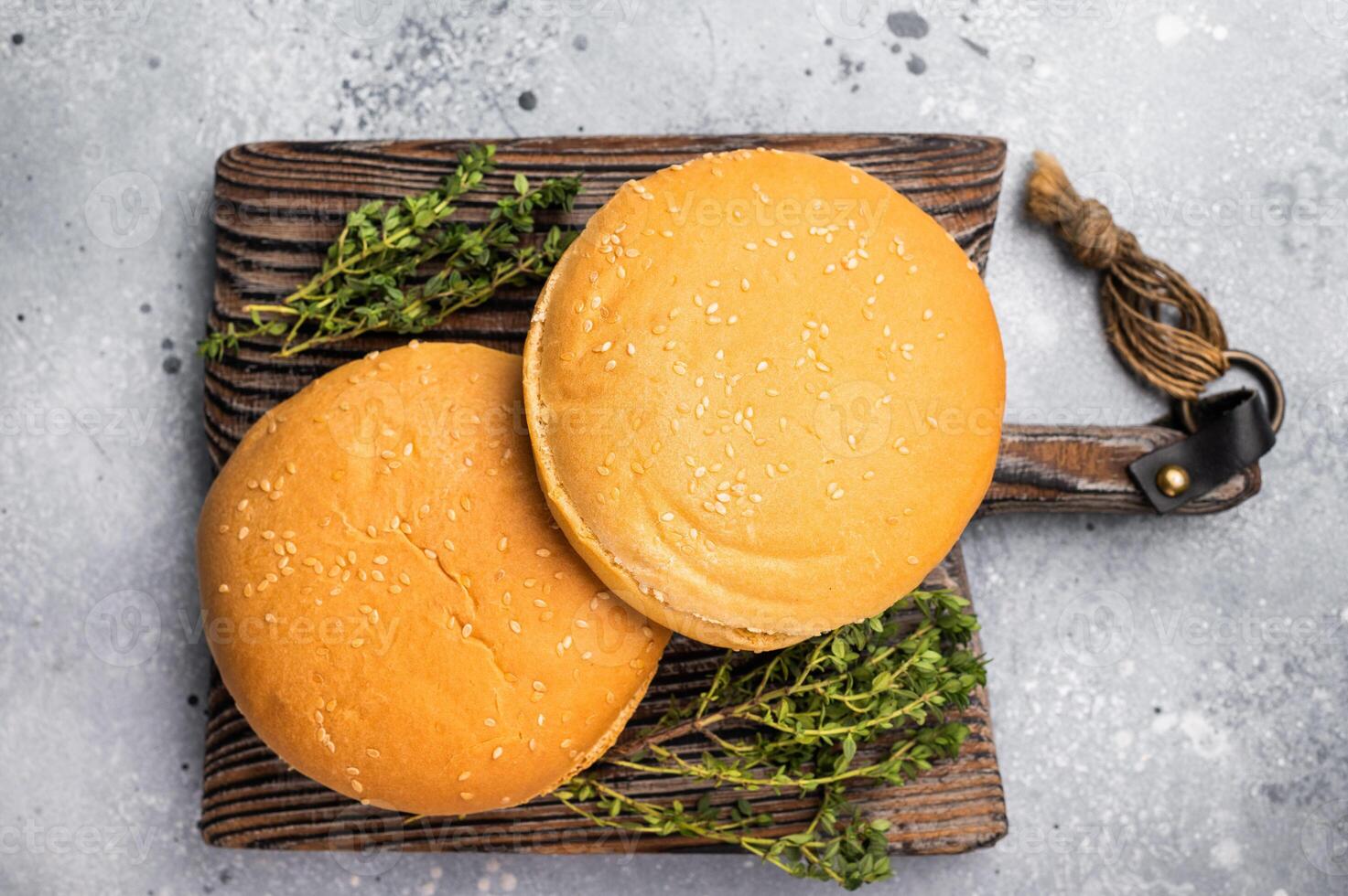 Fresh hamburger buns on wooden board. grey background. top view photo