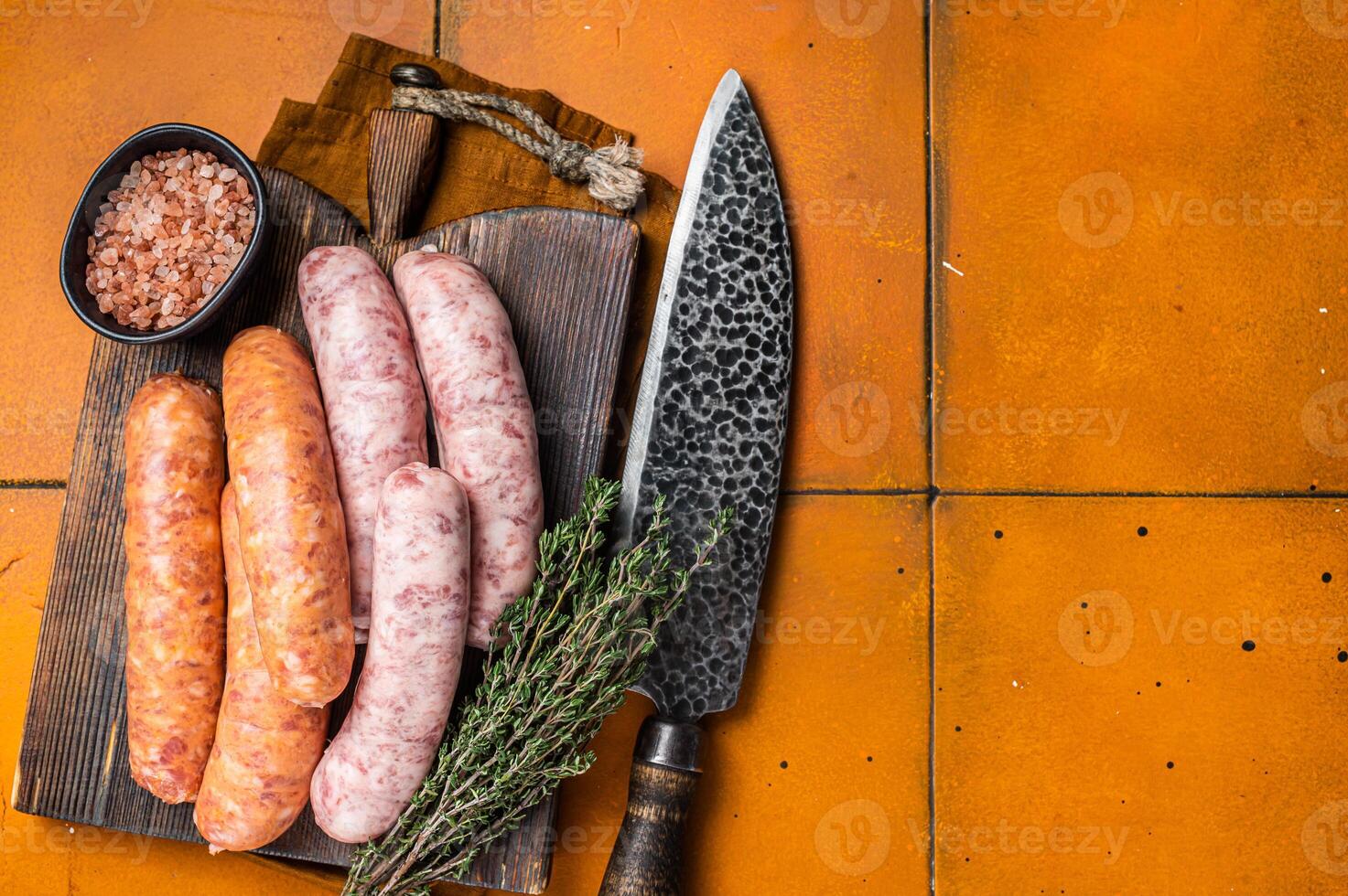 Fresh Raw Bratwurst and Chorizo meat sausages on wooden board. Orange background. Top view. Copy space photo