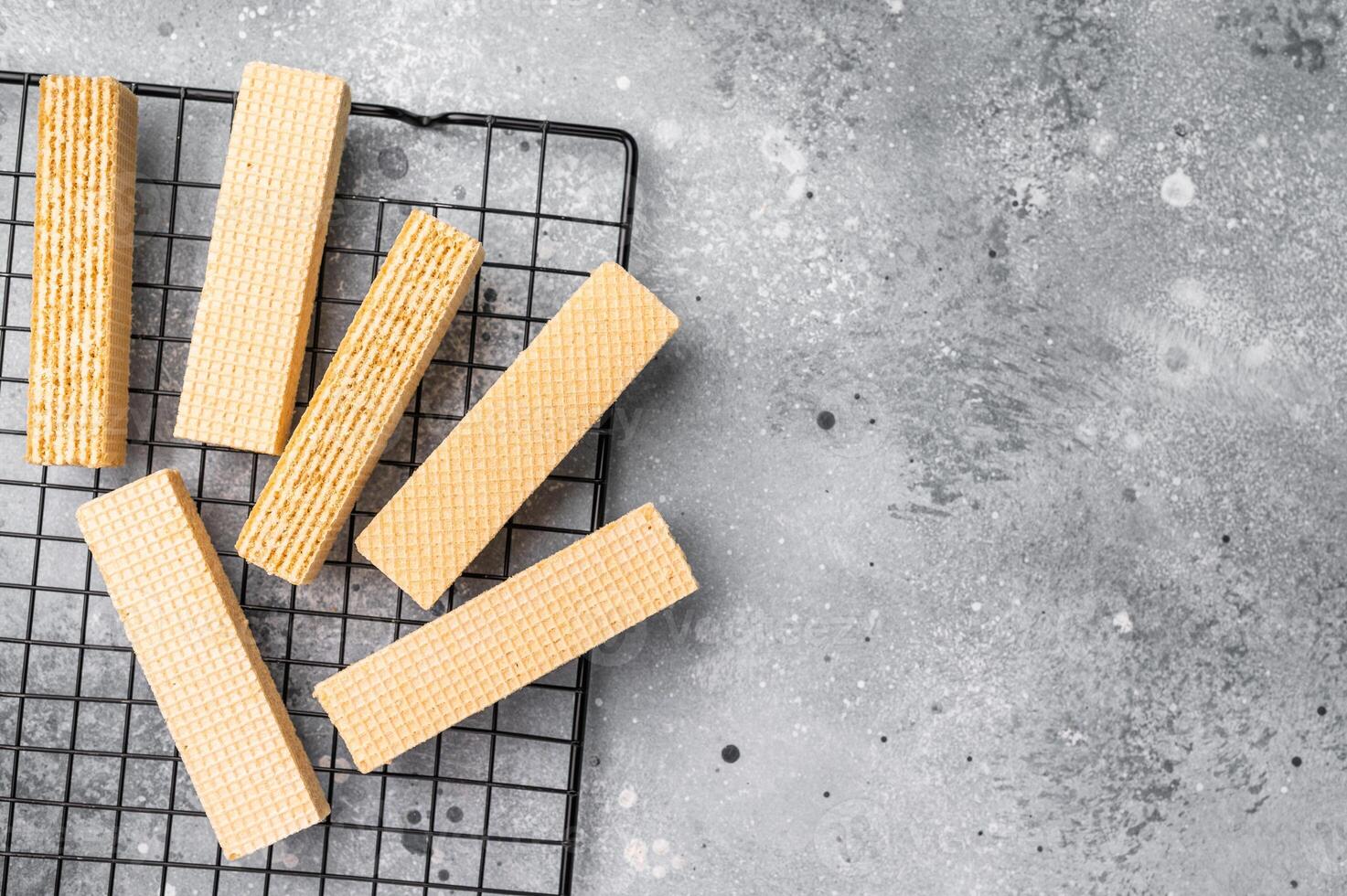 Dry Wafer stick biscuits with vanilla cream on a rack. grey background. top view photo