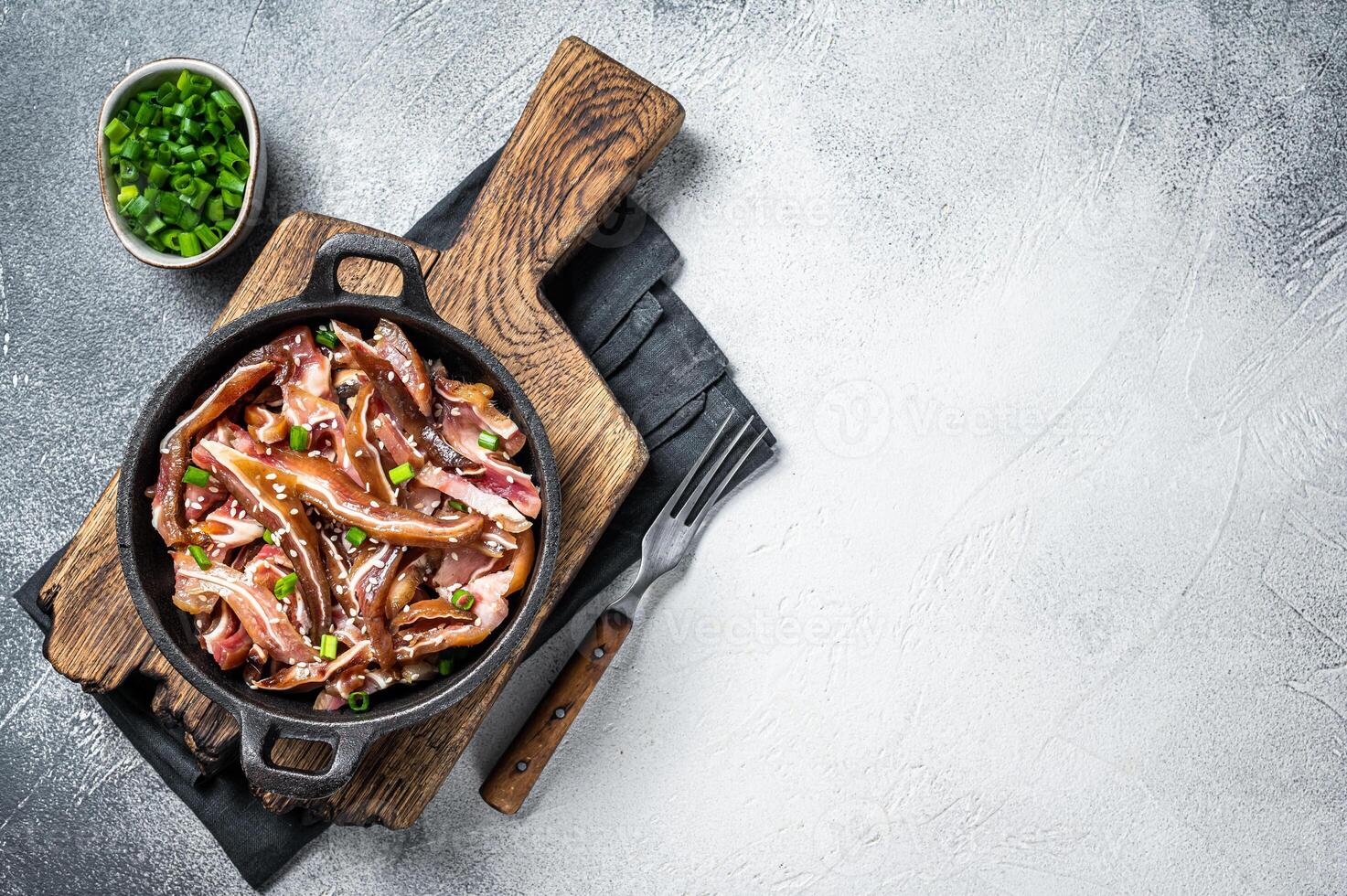 Fried spicy pork pig ears served in a frying pan. white background. Top view. Copy space photo