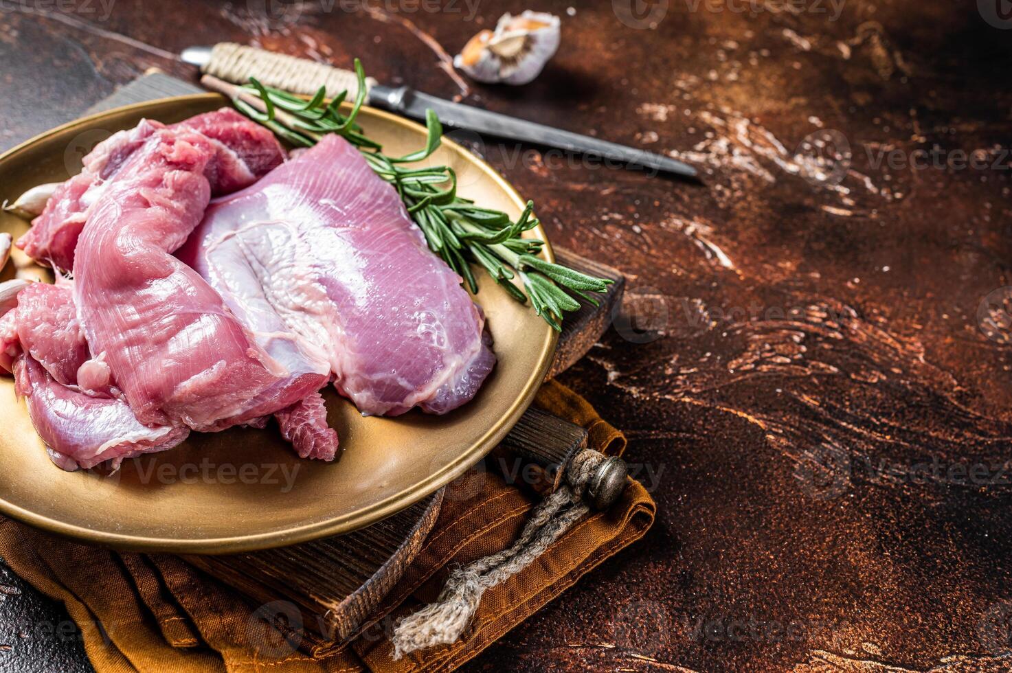 Fresh skinless raw Turkey thigh fillet meat with spices. Dark background. Top view. Space for text photo