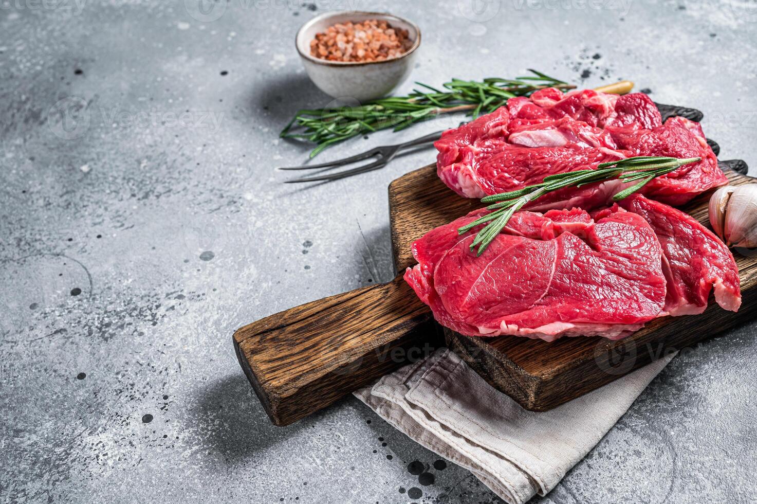 Uncooked Raw Lamb chop leg steaks on cutting board. Gray background. Top view. Copy space photo