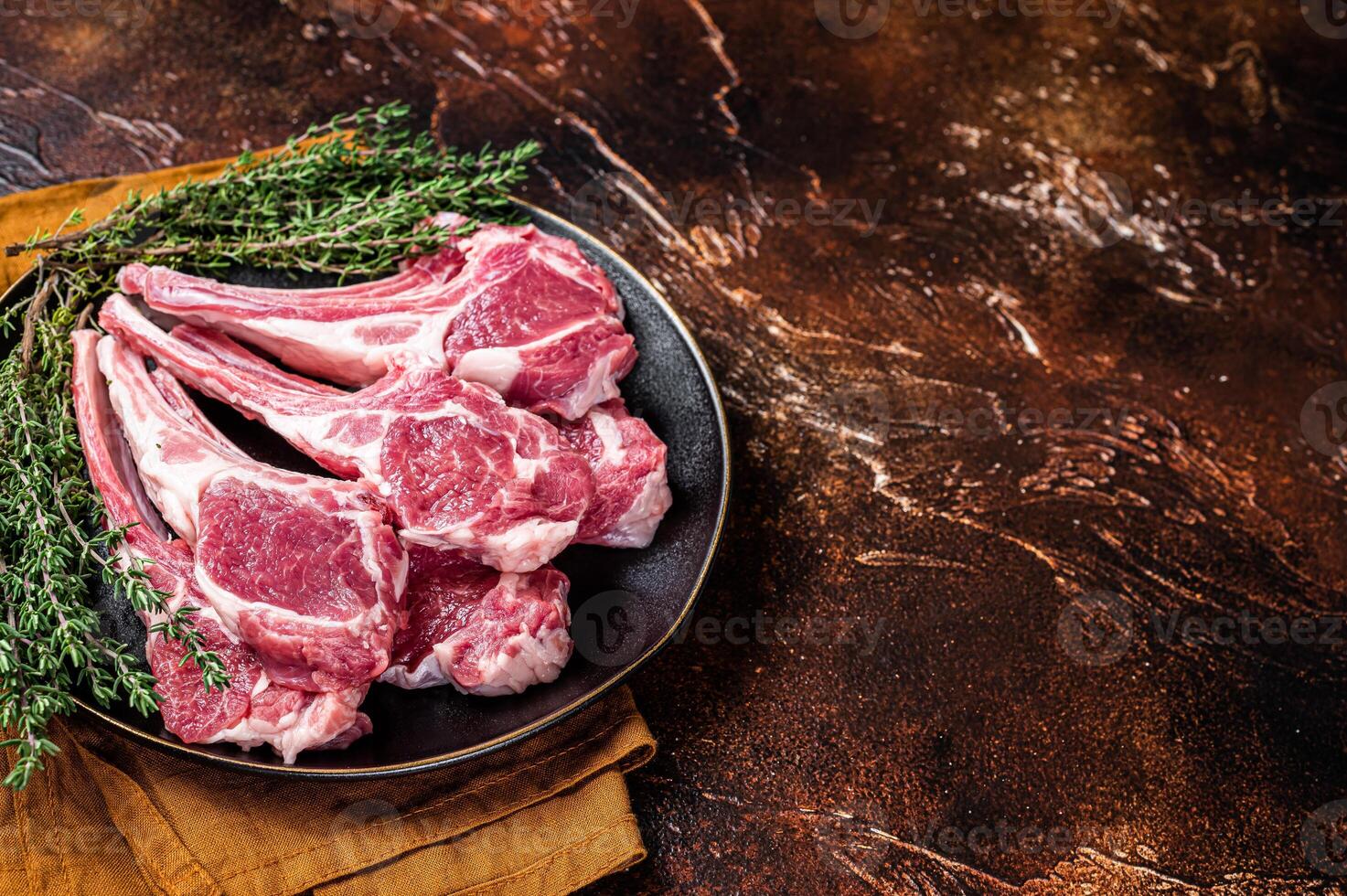 Raw lamb chops, fresh mutton meat cutlets on a ribs. Dark background. Top view. Copy space photo