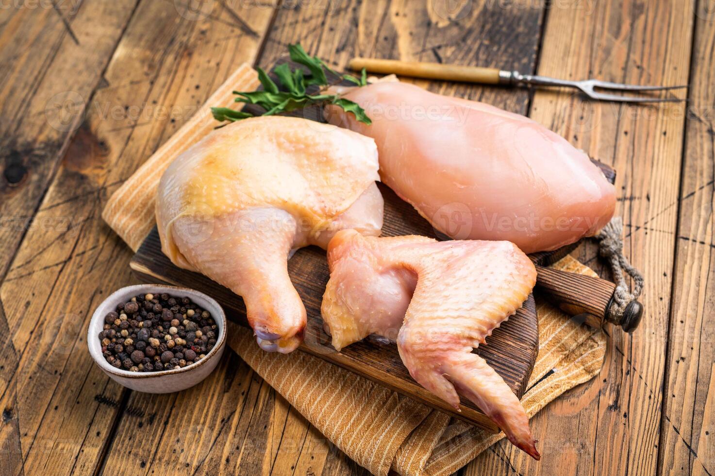 Fresh, raw chicken pieces on a wooden cutting board photo