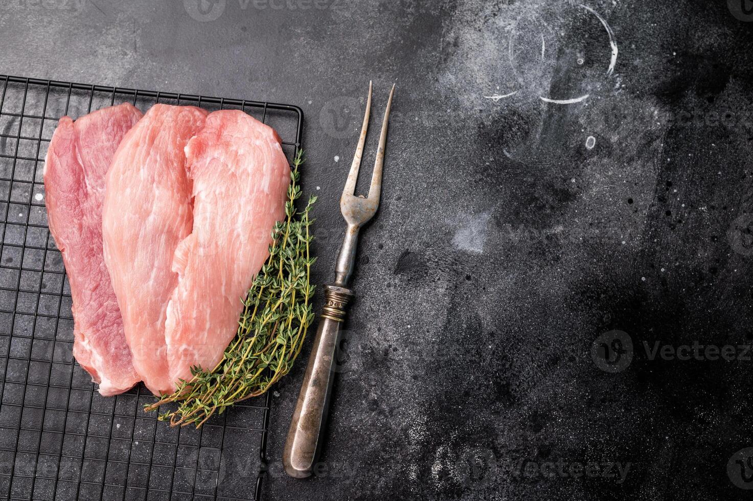 Raw pork fillet meat for schnitzel, steaks on a rack. black background. top view photo