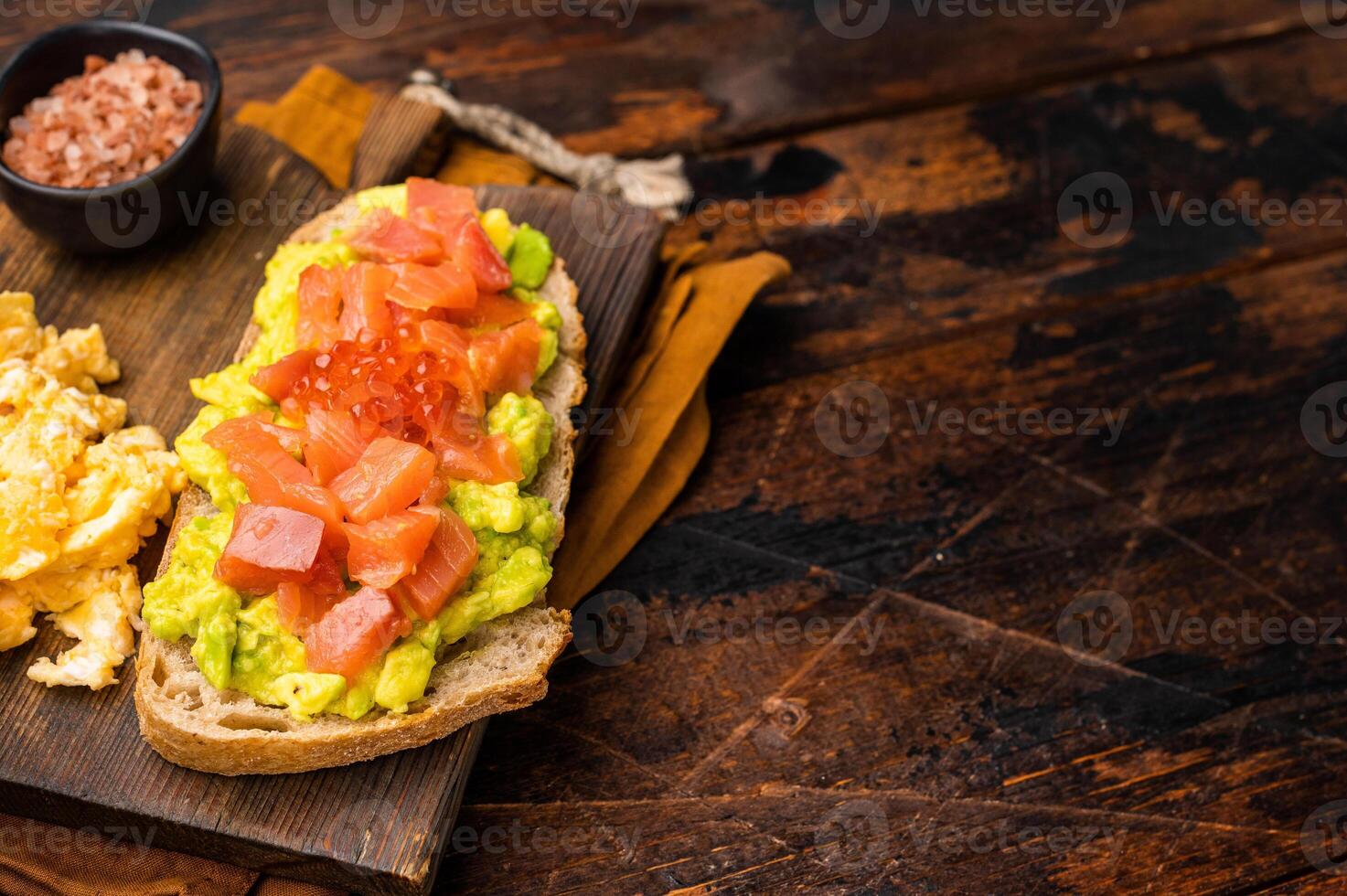 Sandwich with smoked salmon, trout, avocado and red caviar. wooden background. top view photo